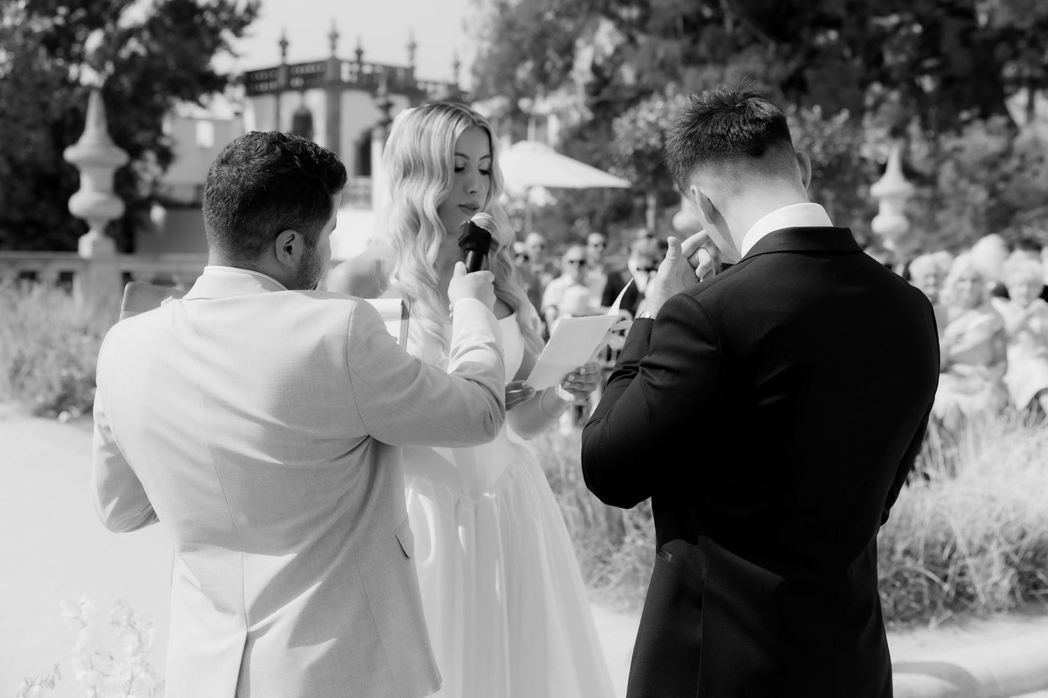 Black and white photo of guests taking pictures with phones and cameras at an outdoor wedding celebration.