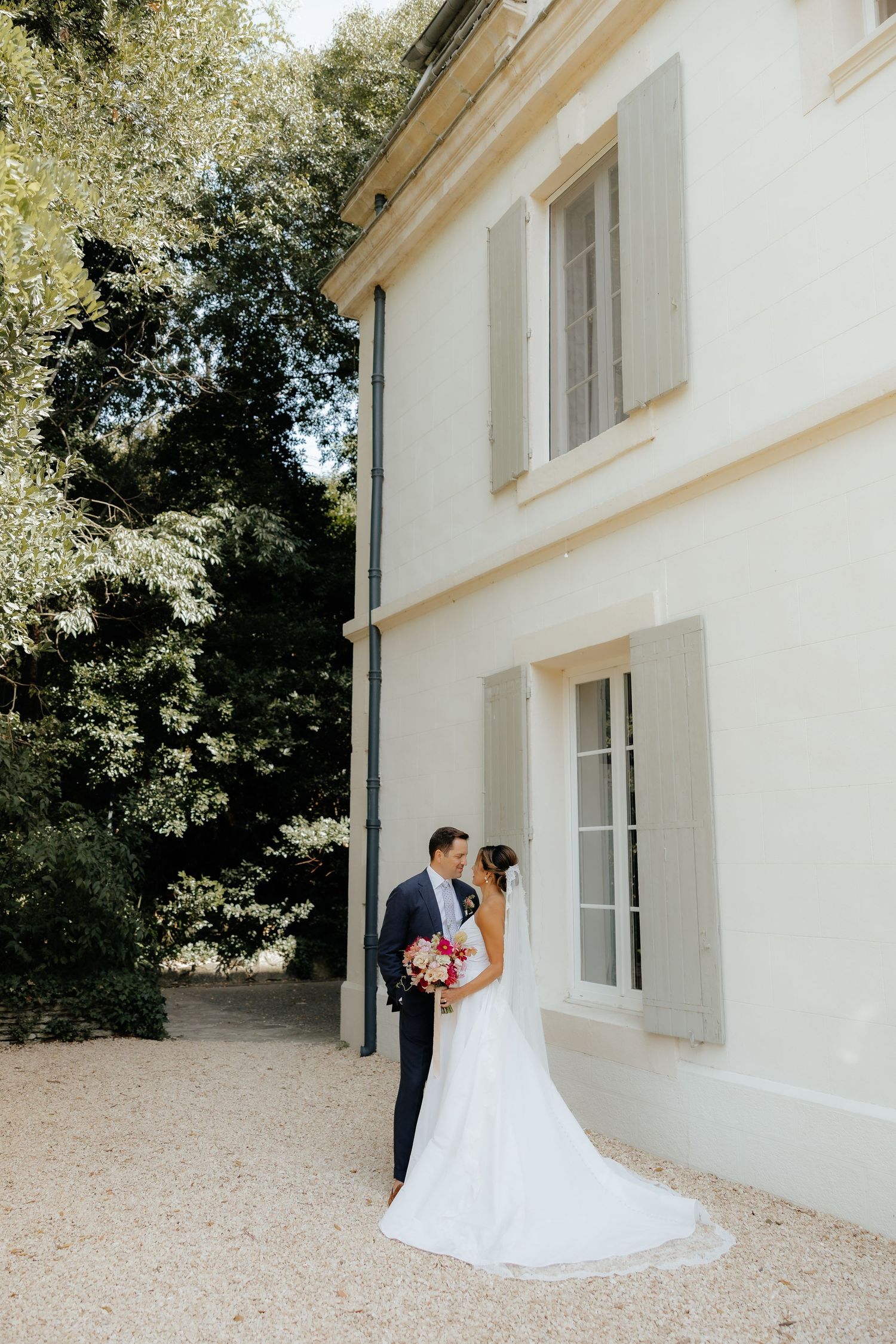 Elegant wedding portraits with bride and groom against white mansion exterior.