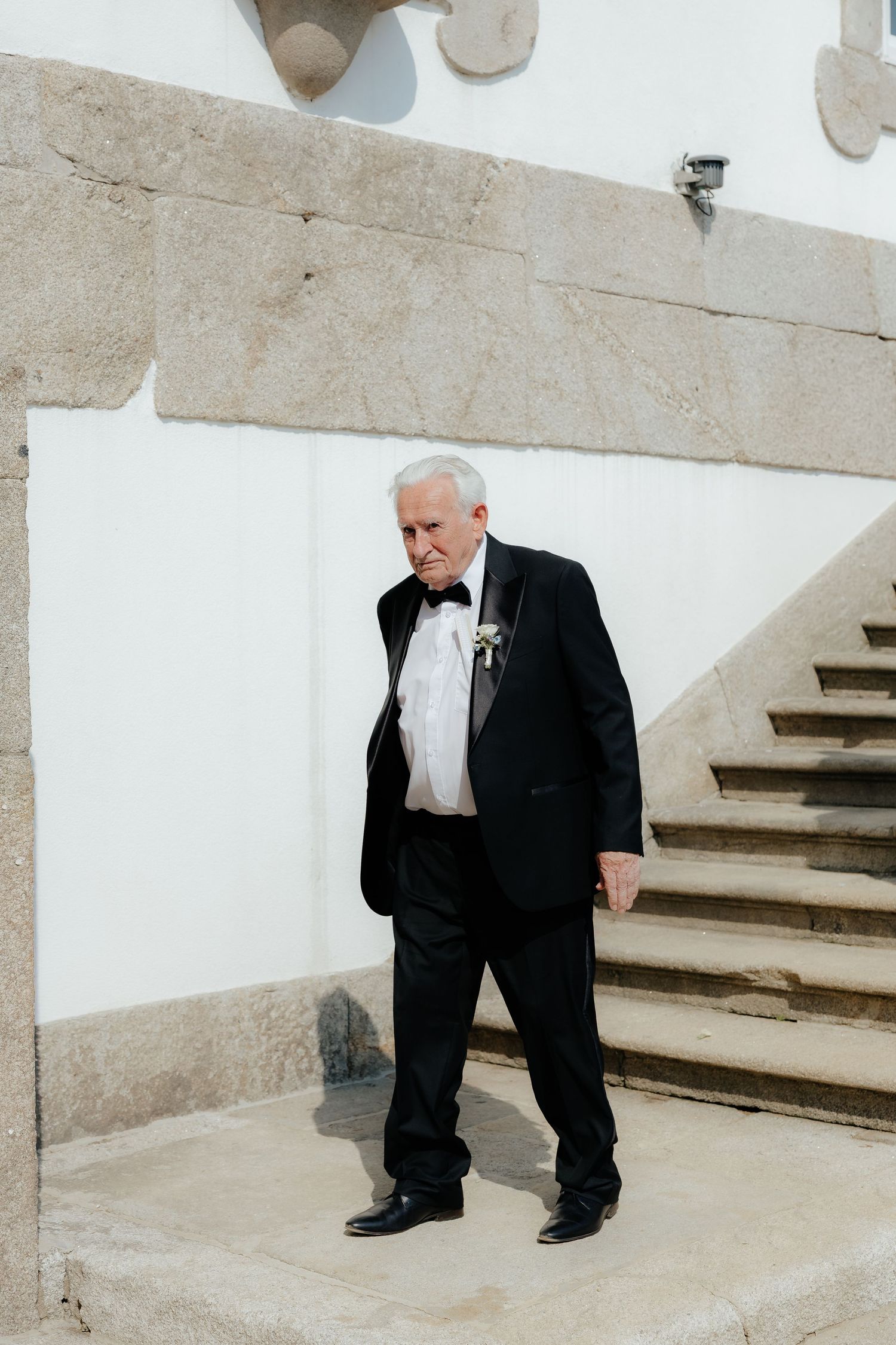 A sequence of four images showing someone in a black suit crouching down on concrete steps in an architectural setting.