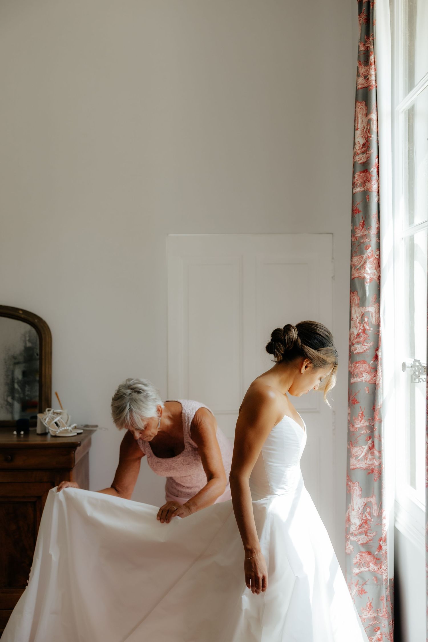 Multiple views of a white dress being steamed and prepared in a sunlit room with floral curtains.