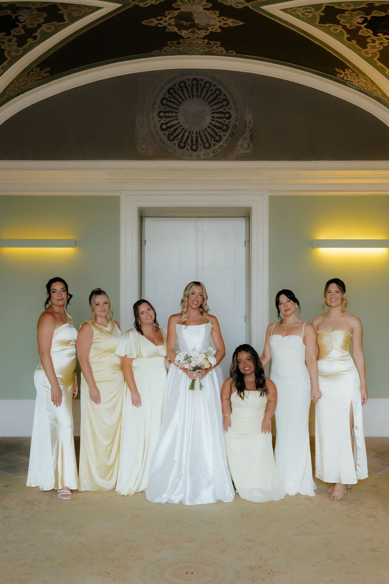 A panoramic series of wedding photos showing bridesmaids in white and cream dresses posing together in an elegant room.