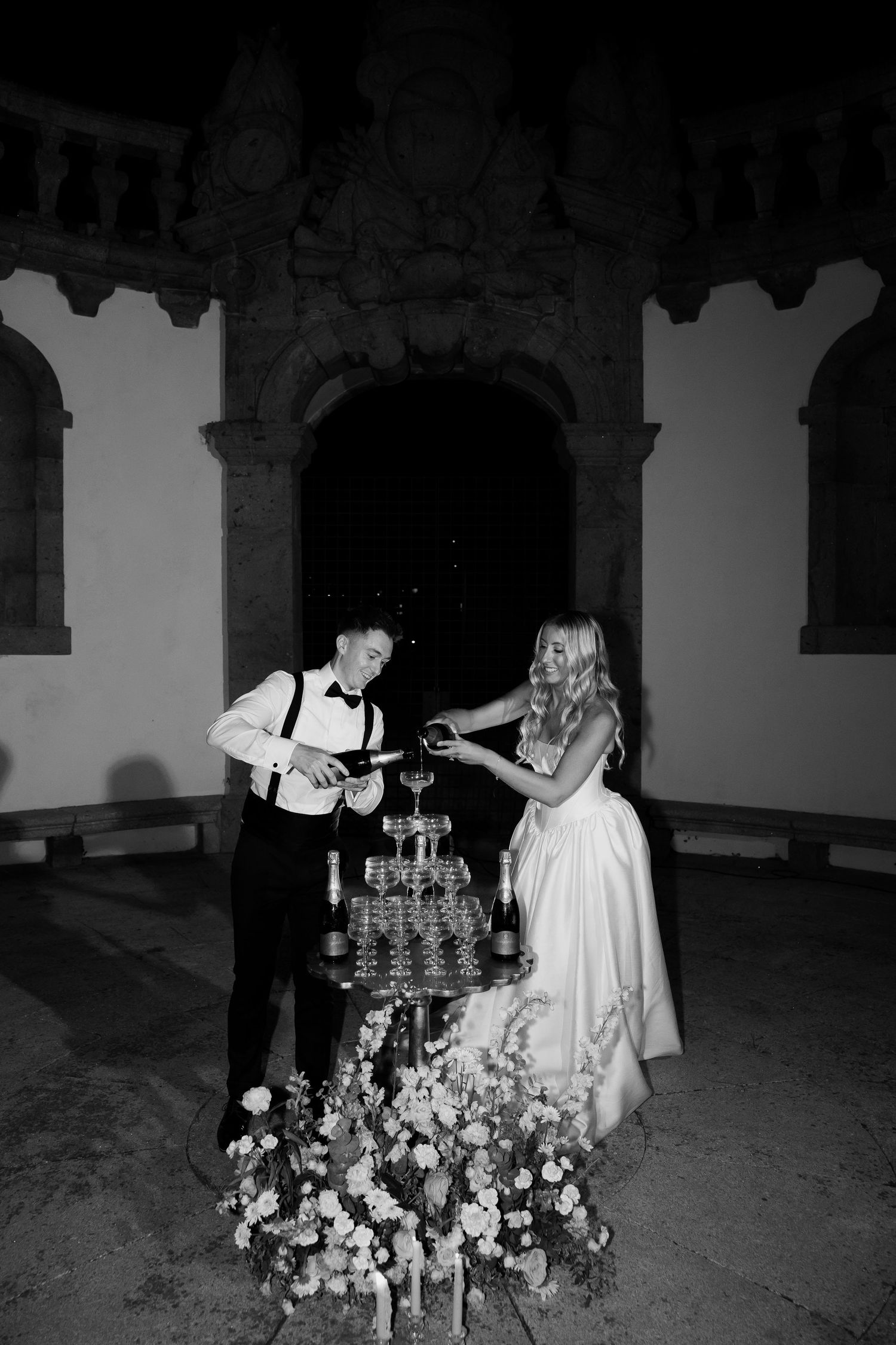 A black and white photo series shows a couple lighting candles during an intimate wedding ceremony in a historic venue.