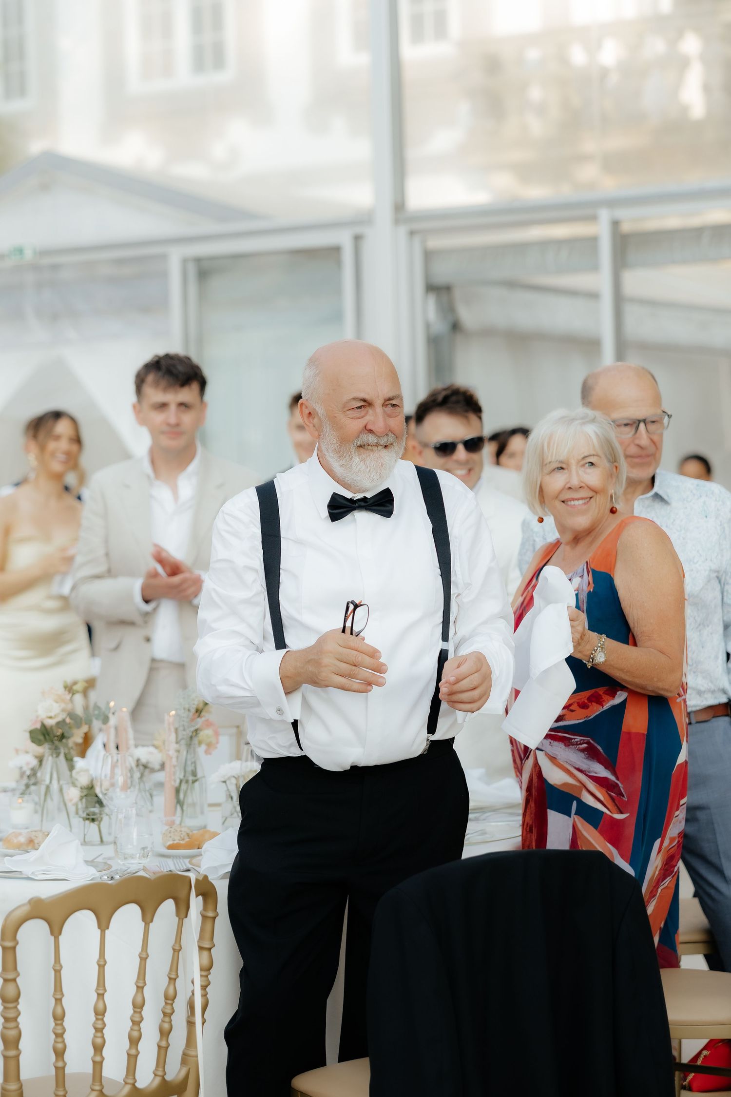 Wedding reception guests in formal attire enjoying a lively celebration at an elegant indoor venue.