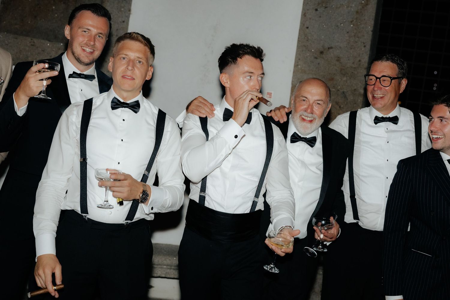 A group of people in formal black and white tuxedos celebrating together at an event.
