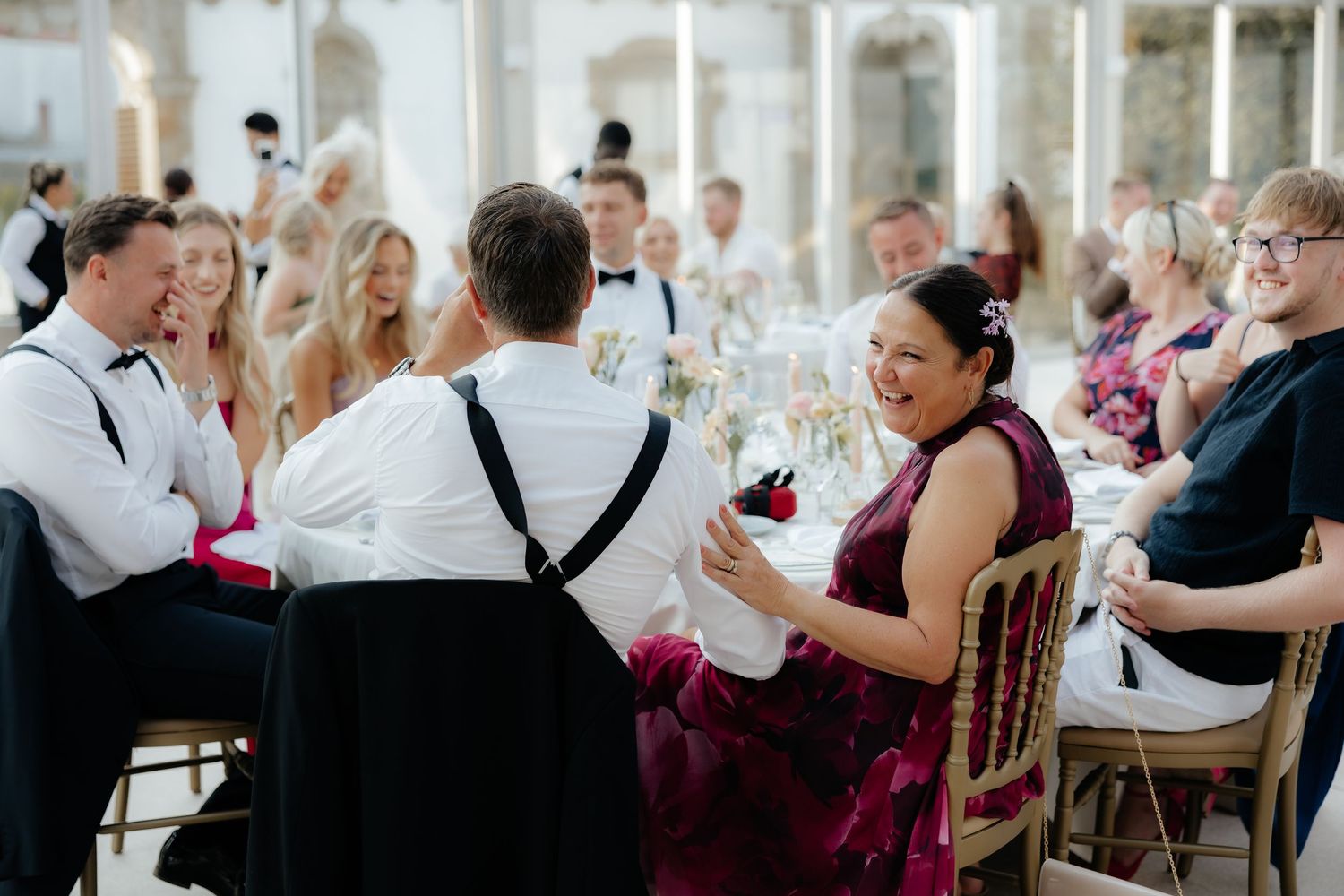Wedding guests seated at reception tables with pink floral centerpieces in an elegant indoor venue.