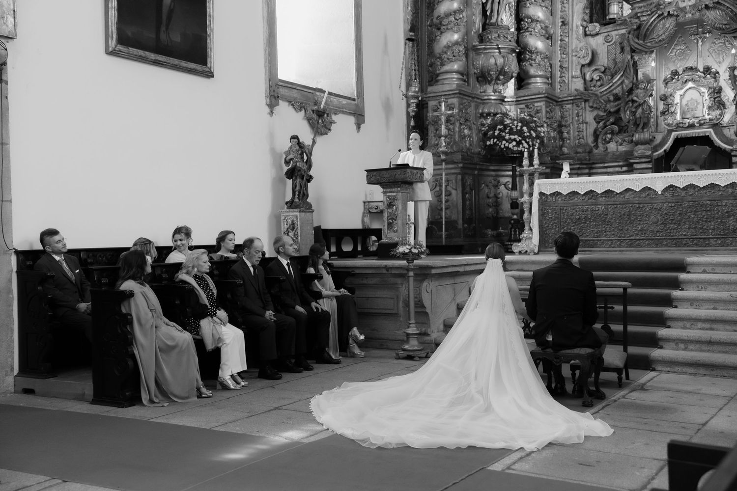 Black and white photo of bride in long veil during church wedding ceremony.