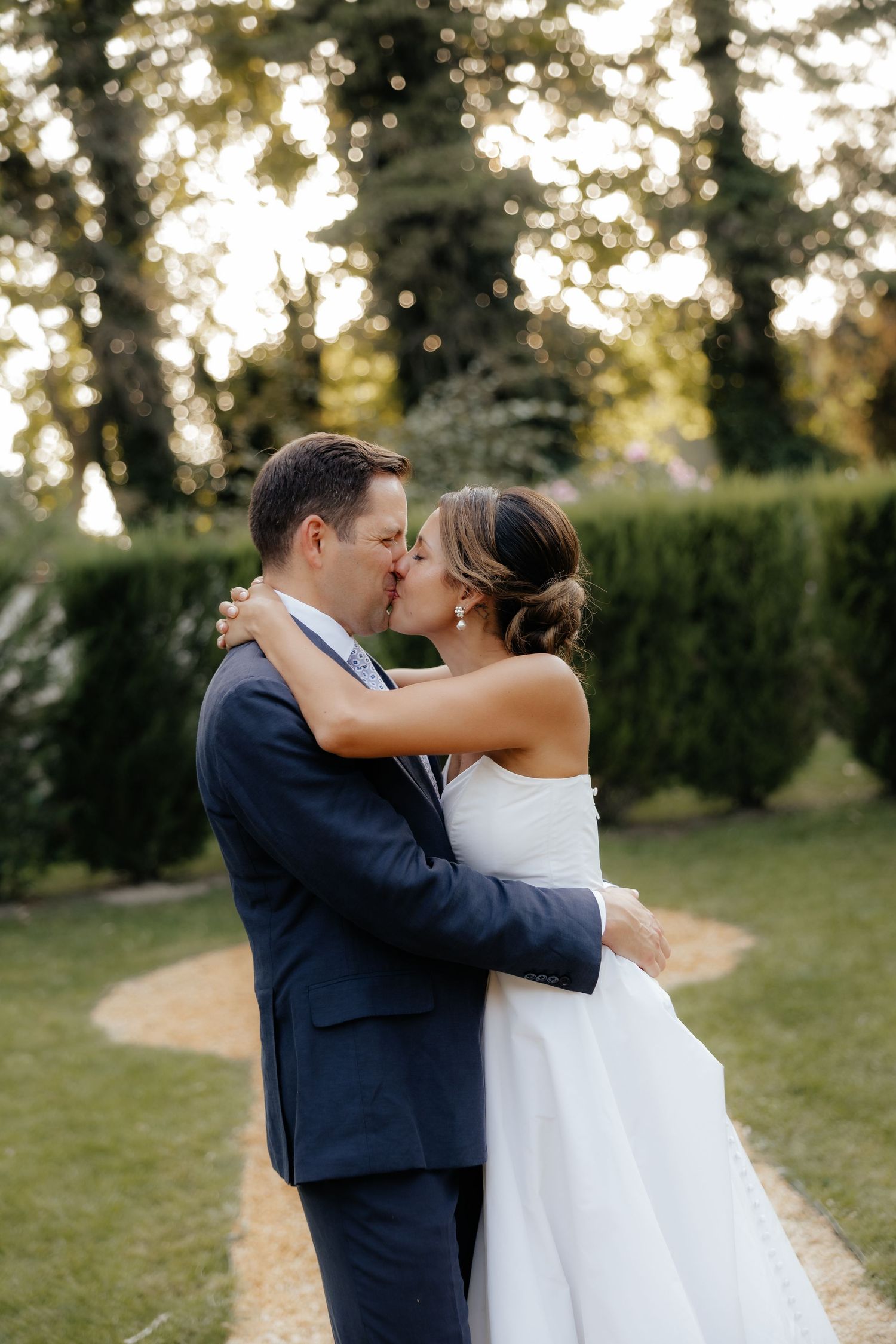A romantic sunset wedding portrait captured in a garden setting with golden light.