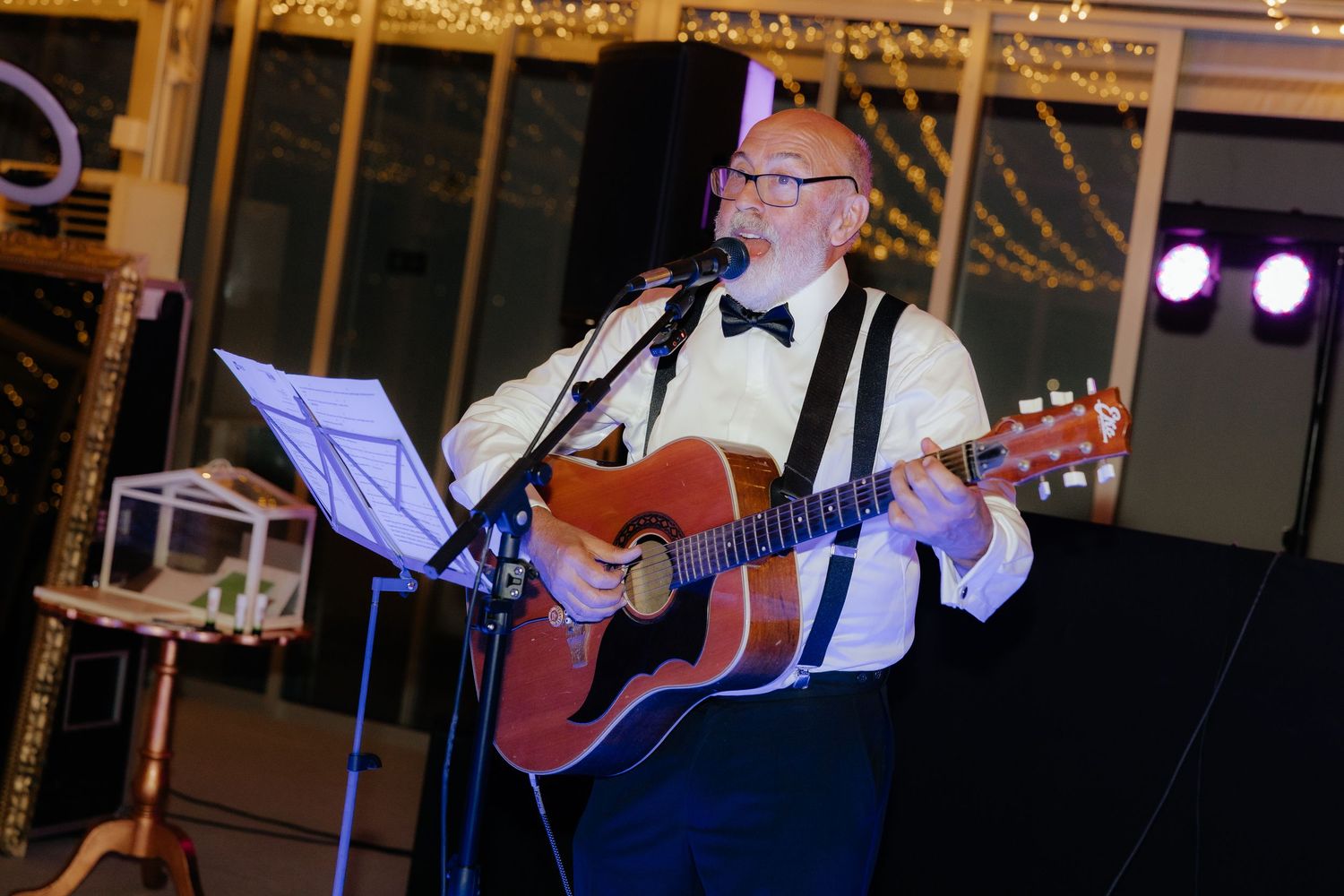 Musicians in black and white formal attire perform with acoustic guitars at an elegant event venue.