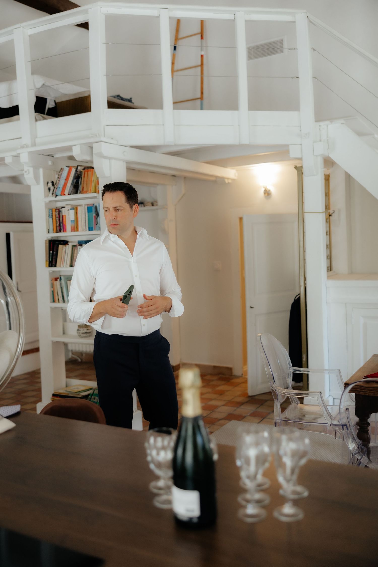 Interior of a bright white room with bookshelves and wooden furniture during a wedding preparation.