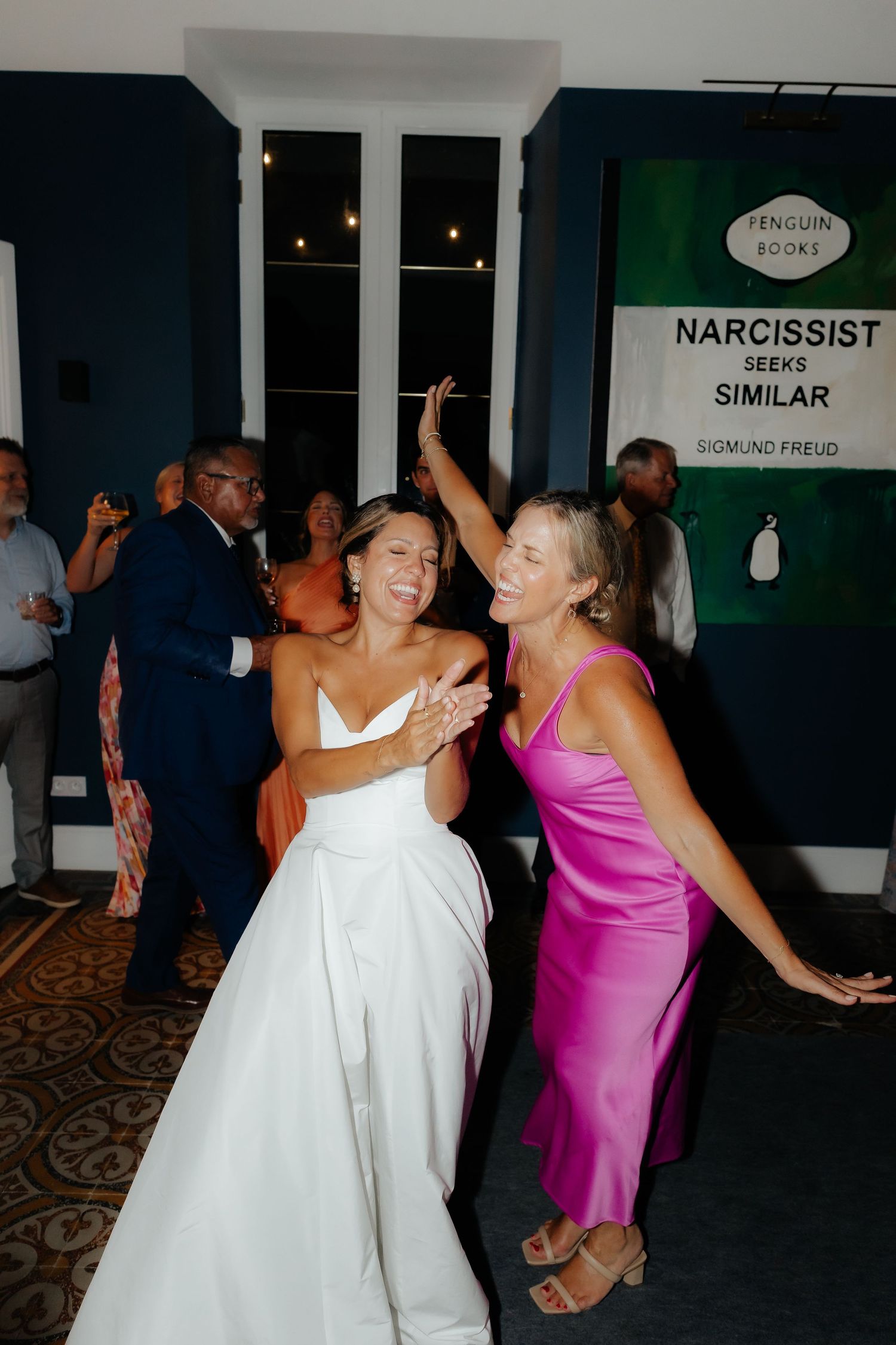 Wedding guests dance and celebrate together at a reception with people in white and pink dresses.