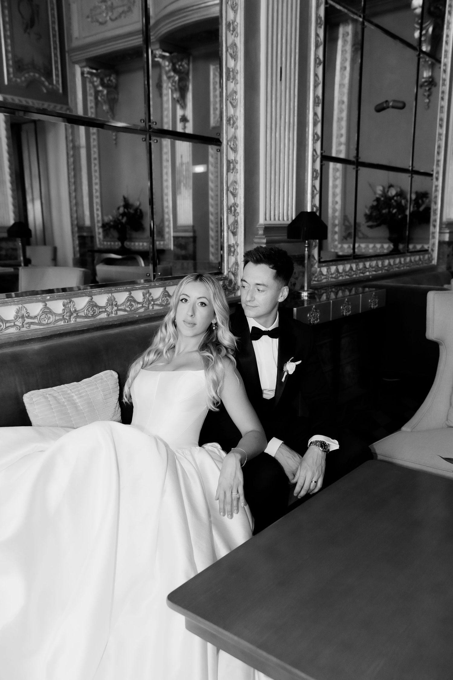 A black and white photo series showing a couple in formal attire lounging on vintage furniture in an elegant room.