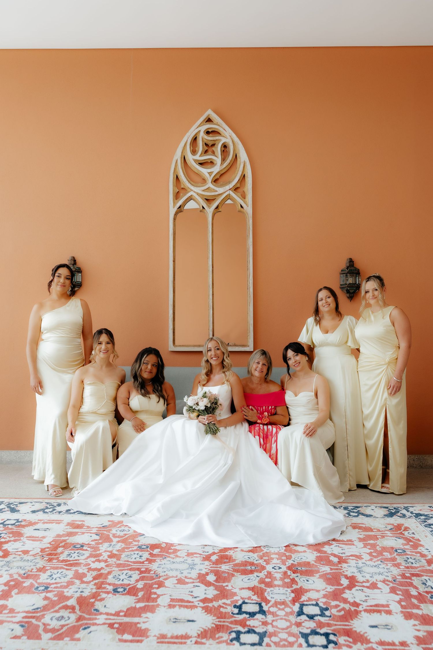 A sequence of wedding party photos showing bridesmaids in cream dresses posing playfully on a peach-colored wall backdrop.
