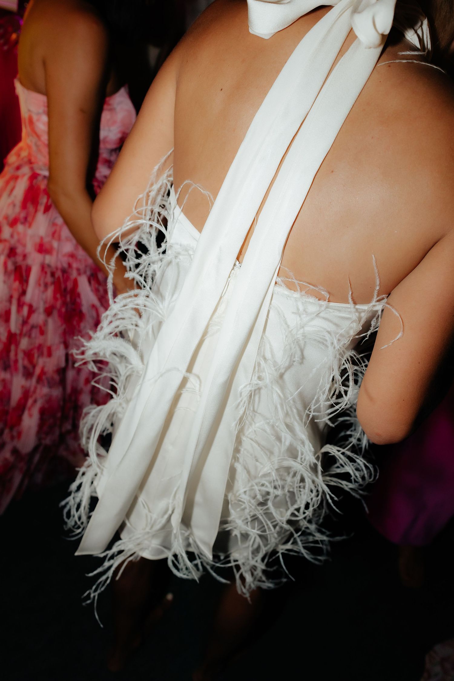 Close-up details of a white feathered dress with delicate ostrich plumes creating elegant texture and movement.
