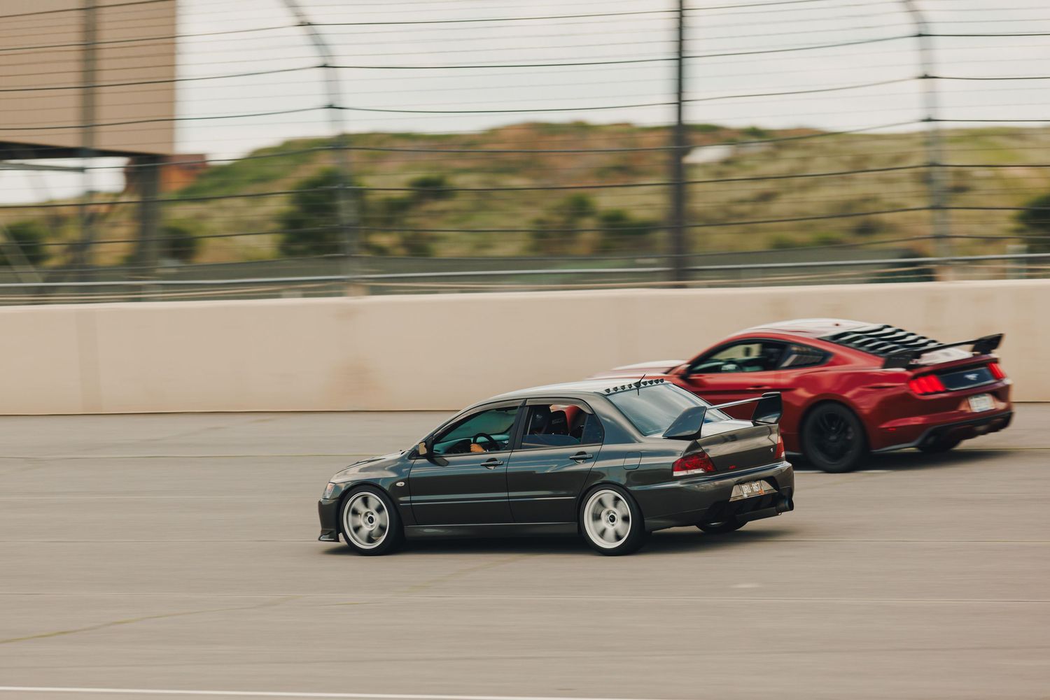 Grey Evo 9, passing by a red mustang while racing at Pikes Peak International Raceway in Colorado Springs, Colorado