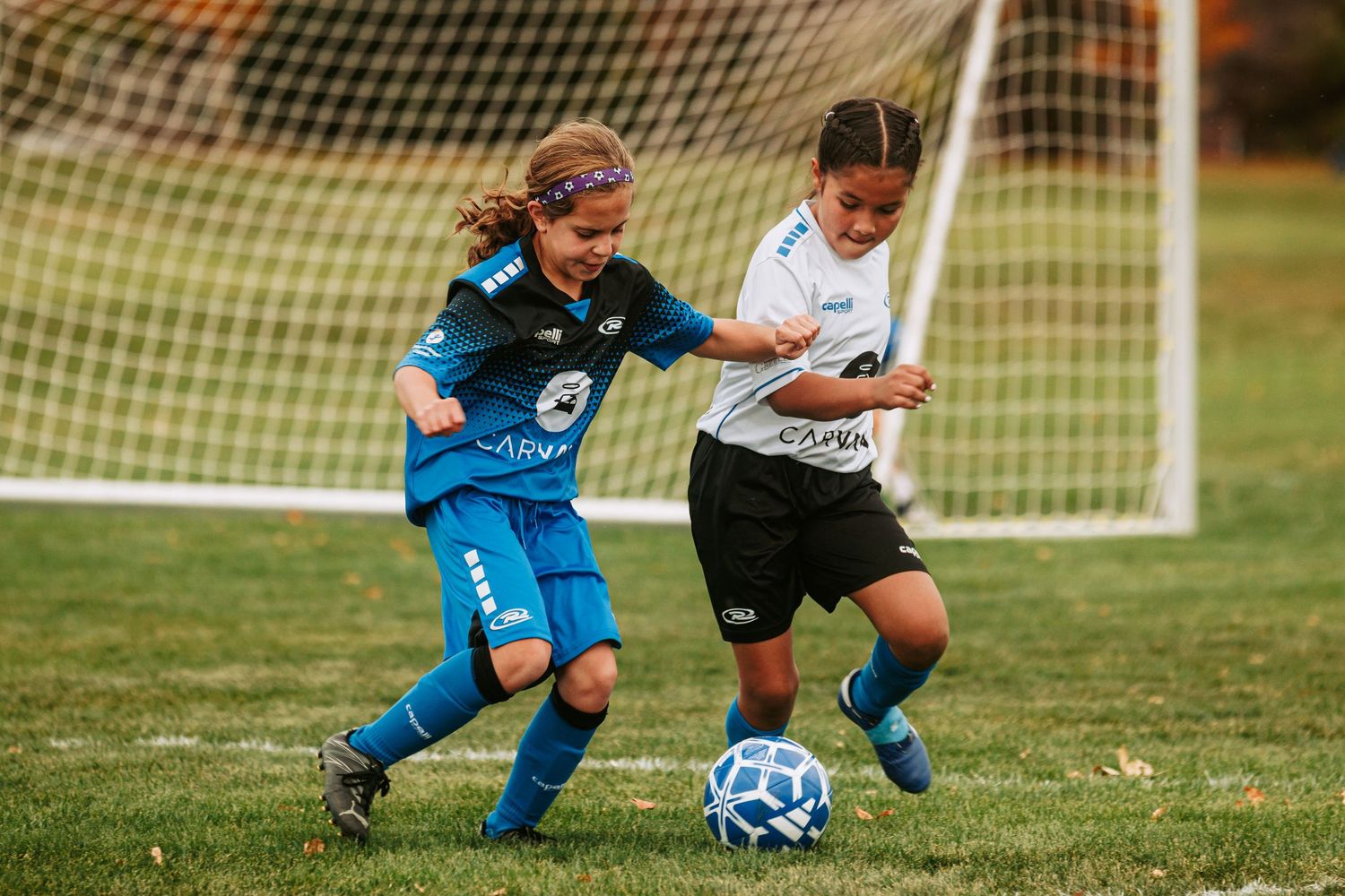2 girls rushing to a soccer ball to retain possession of the ball during a NORCO Rush Soccer game.