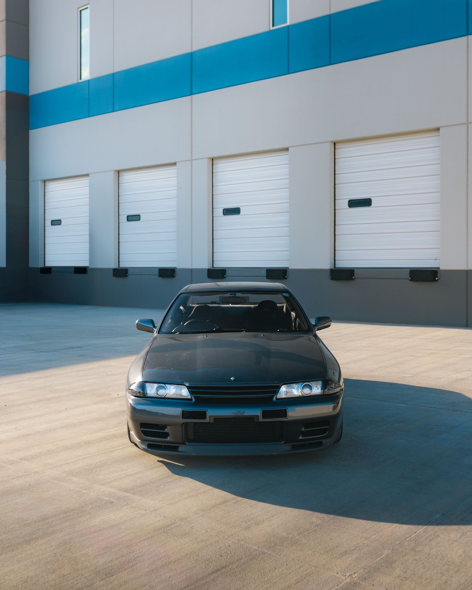1990 Nissan Skyline GTR R32, front profile shot at a warehouse during sunset
