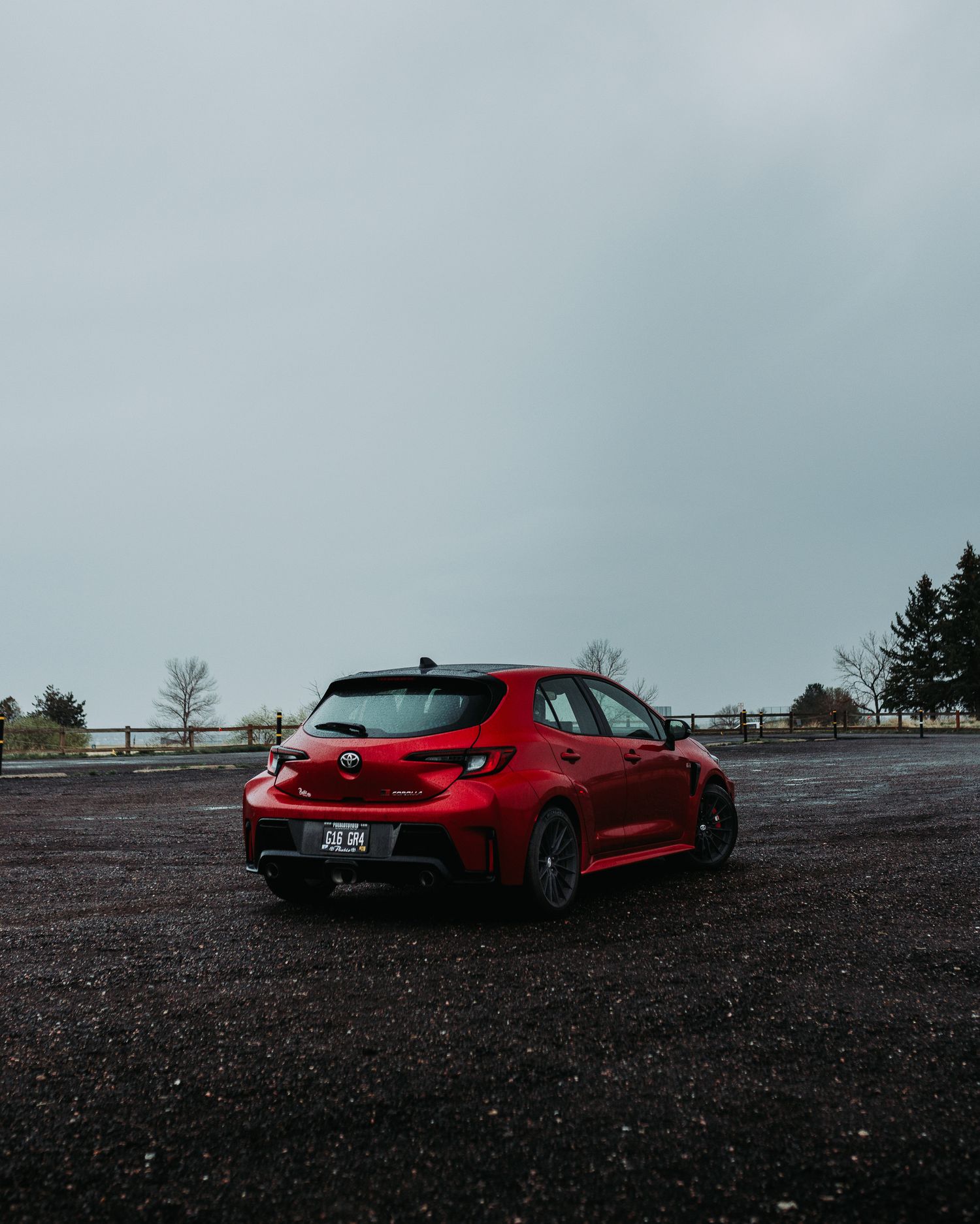 Wide angle rear quarter shot of Red GR Corolla during a rain storm