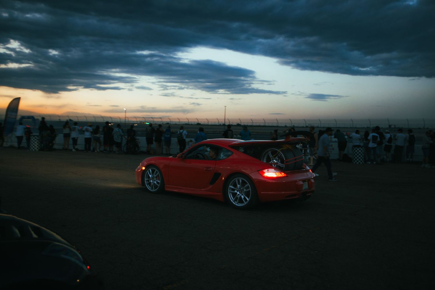 Red Porsche 911, driving during blue hour sunset, carrying a spare tire for drifting after a long track day at PPIR in Colorado Springs, CO