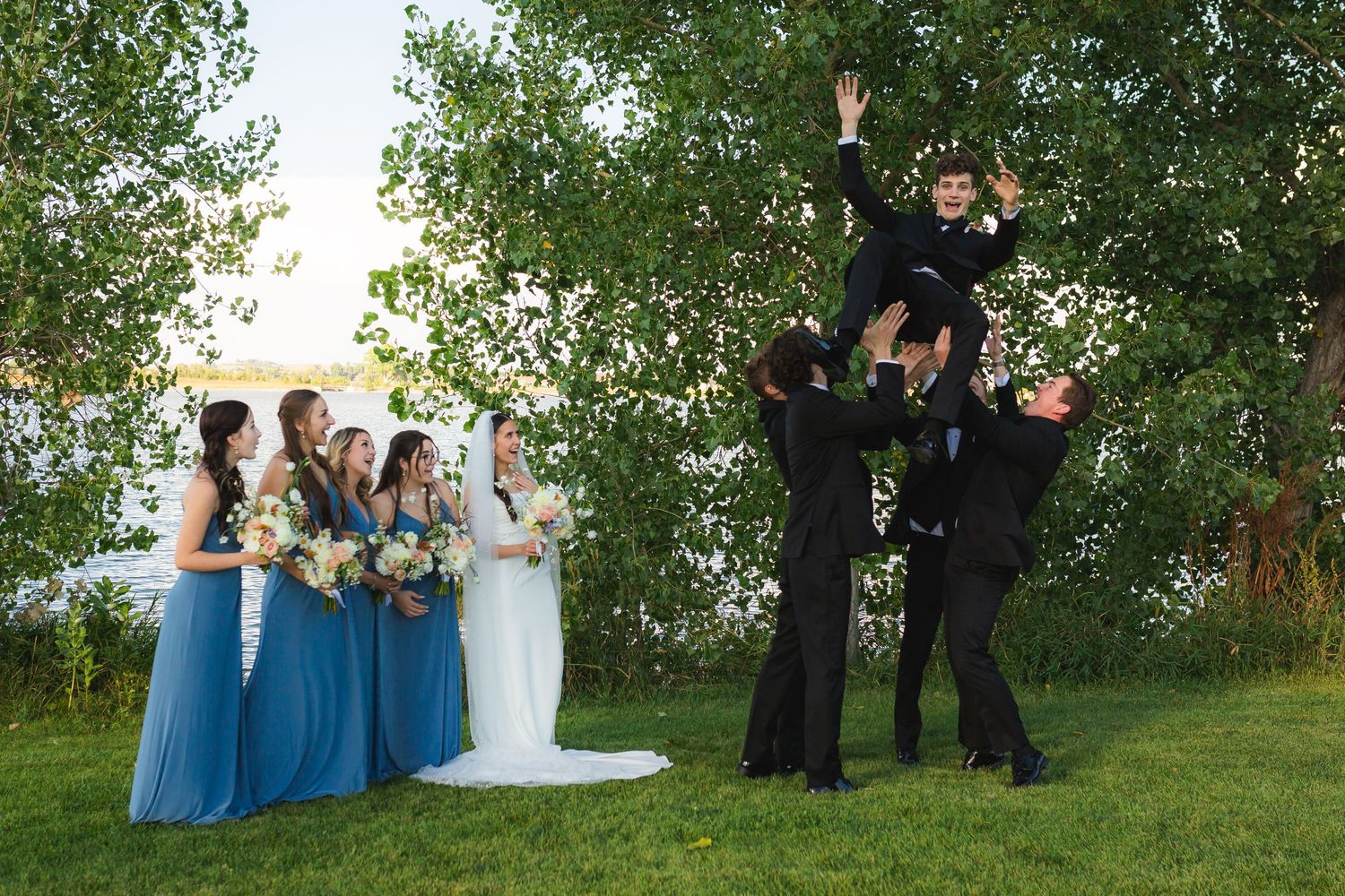 Storrie/Longoria Wedding, bridal party watching as the groomsman toss groom in the air at The Windsor Mill Event Center