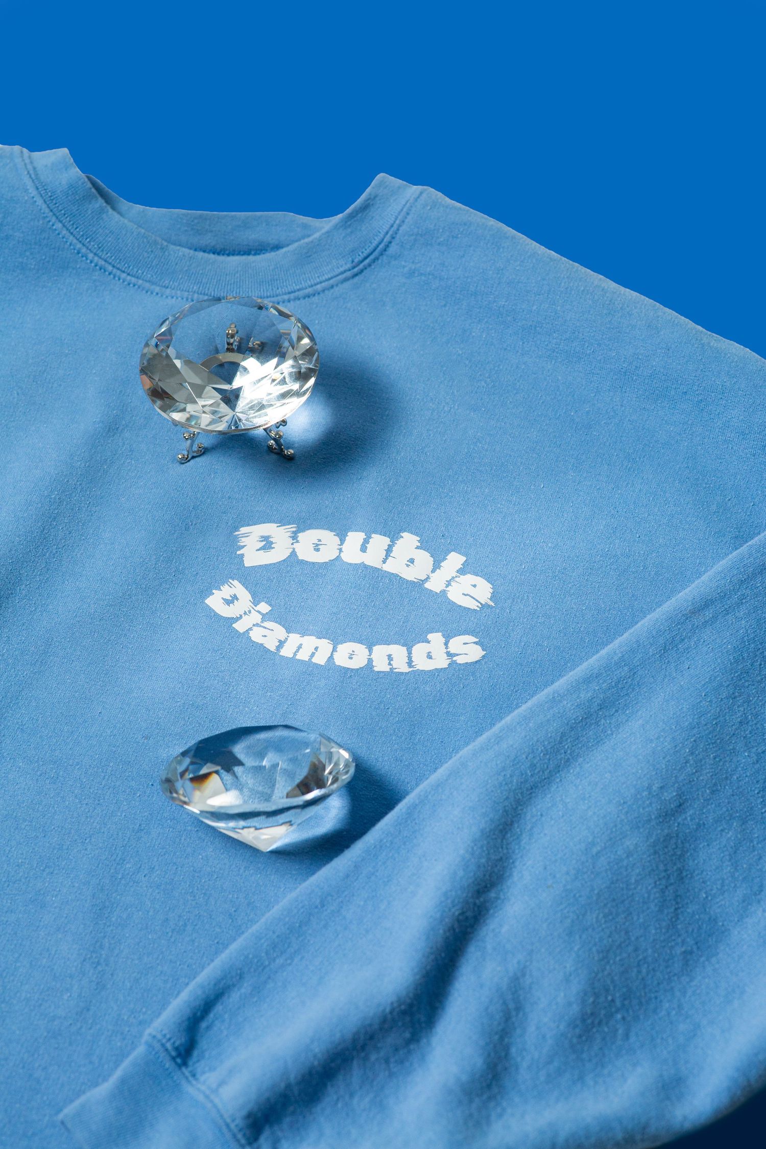 Close up, creative product shot of Double Diamonds blue crew neck with 2 diamonds