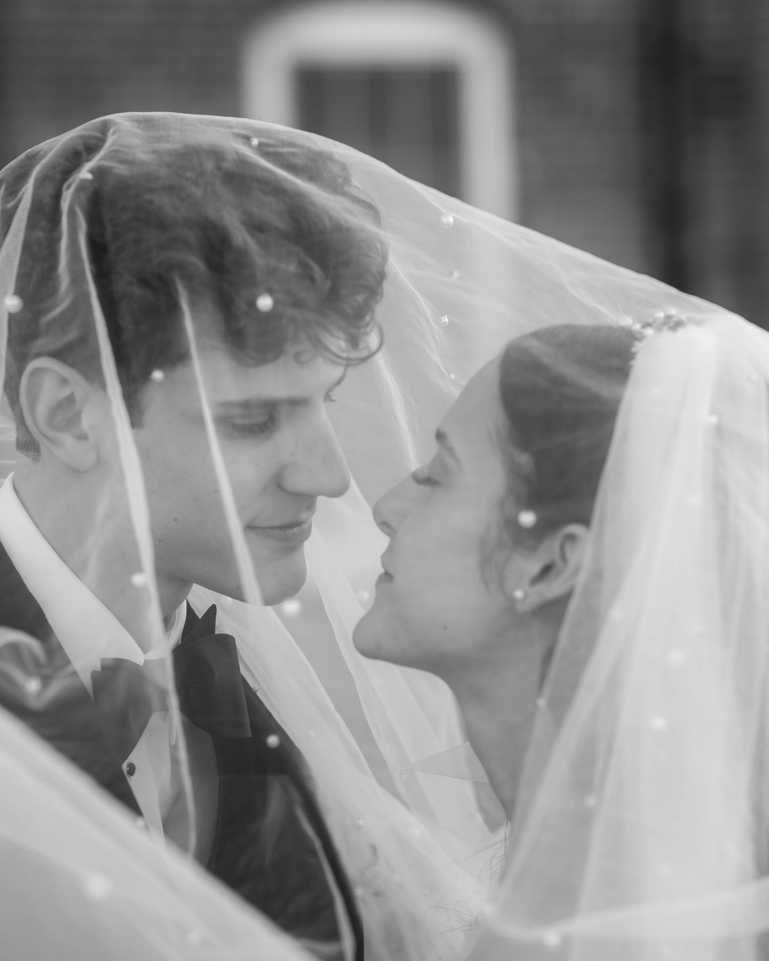 Storrie/Longoria Wedding, black and white photo of couple embracing each other under the bride's veil, after wedding vows at The Windsor Mil
