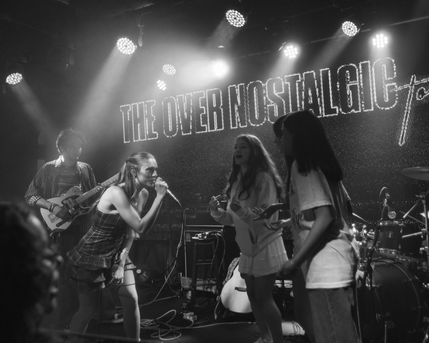 Black and white, wide angle shot of Kenzie Cait, performing with fans on stage while on The Over Nostalgic Tour at Lost Lake Denver