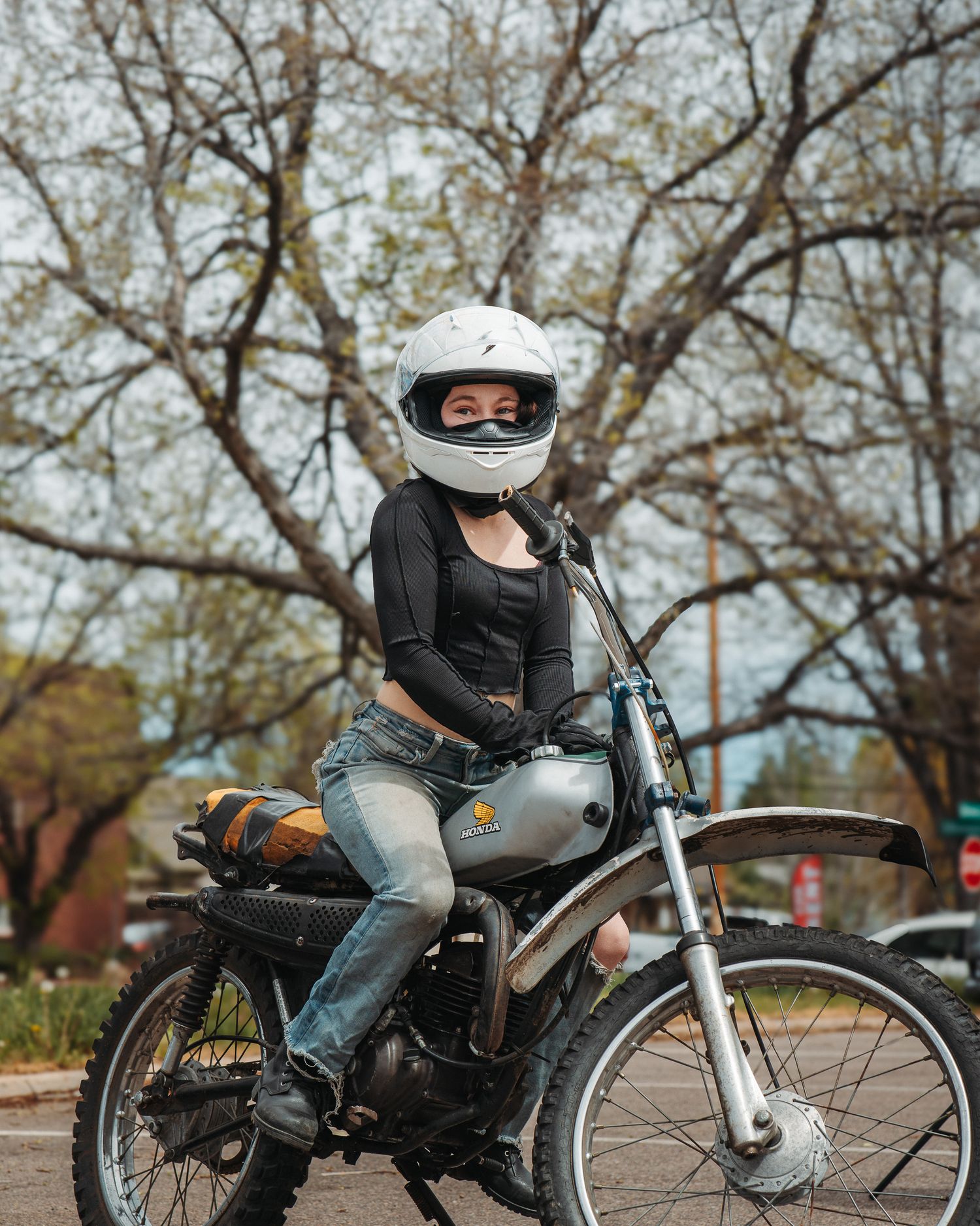 Woman with motorcycle helmet, straddling motorcycle with hands on gas tank, portrait session