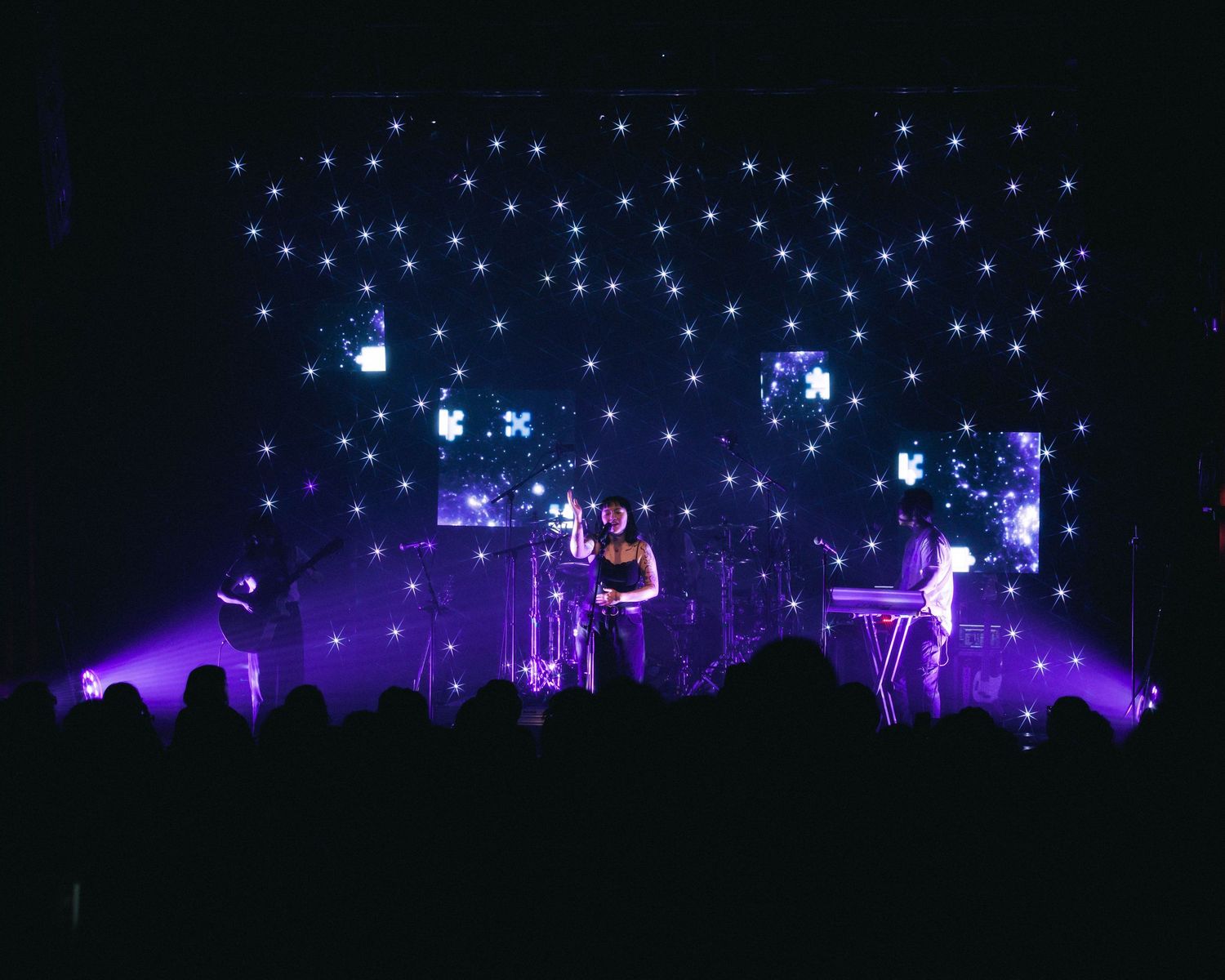 Wide angle of mxmtoon on star lit stage, performing on her Liminal Space Tour at Gothic Theater in Denver, Colorado