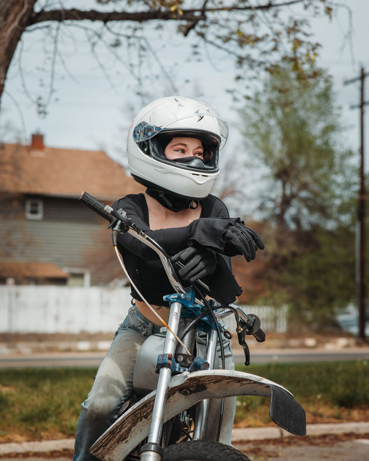 Woman with motorcycle helmet, straddling motorcycle with hands on handle bar, portrait session