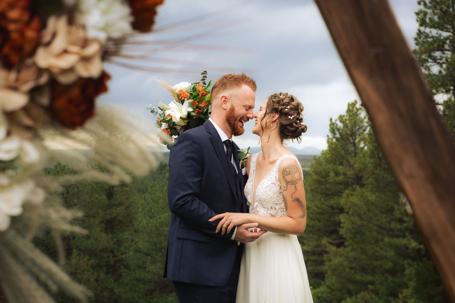 Creative shot of bride and groom smiling and embracing eachother with beautiful colorado trees in the background.