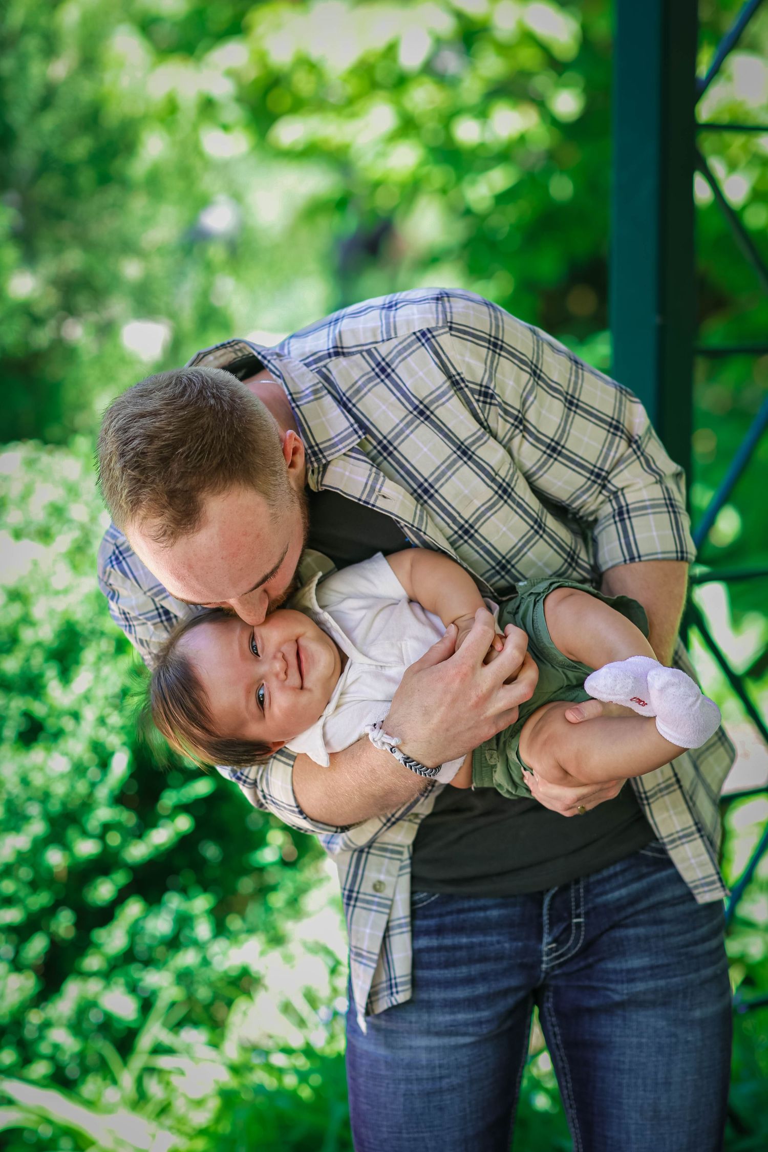 Father embracing his child, kissing him on the cheek and laughing together, at the Denver Botanic Gardens