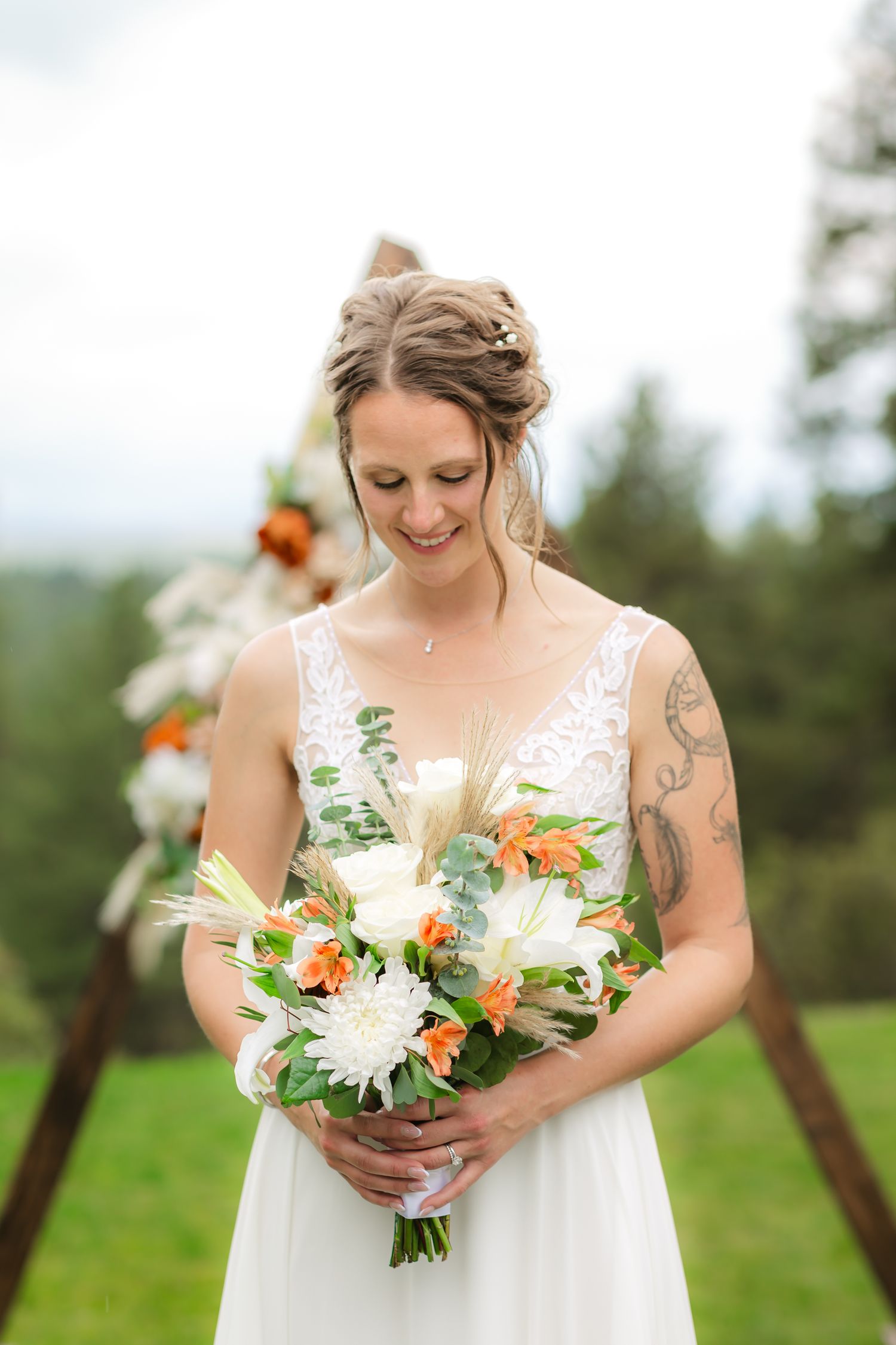 Wolfe Wedding in Franktown, Colorado, close up of bride holding and looking at her beautiful bouquet.
