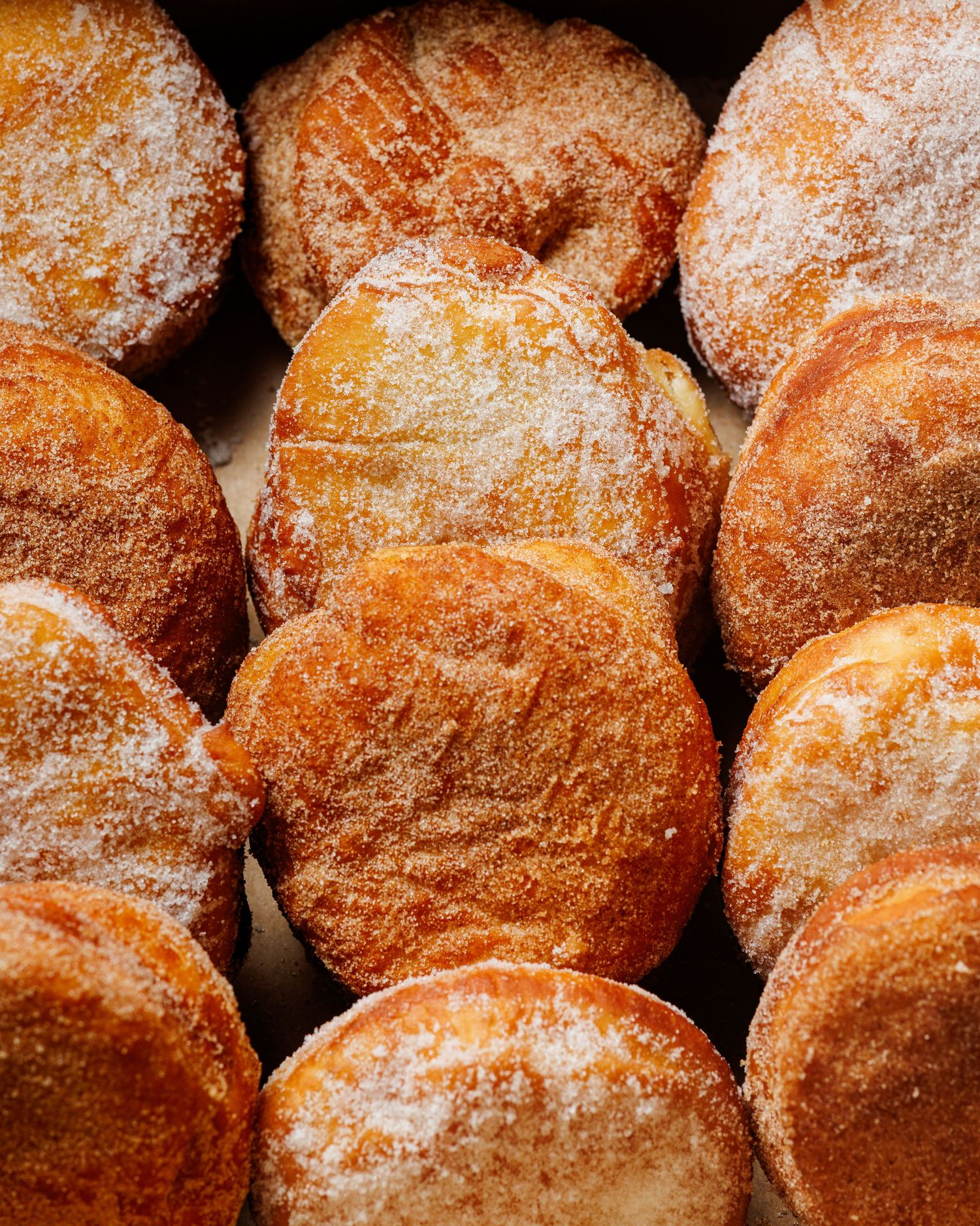 Close up shot of a freshly fried, sugar coated, malasada from TropiTai Delights Dessert Shop