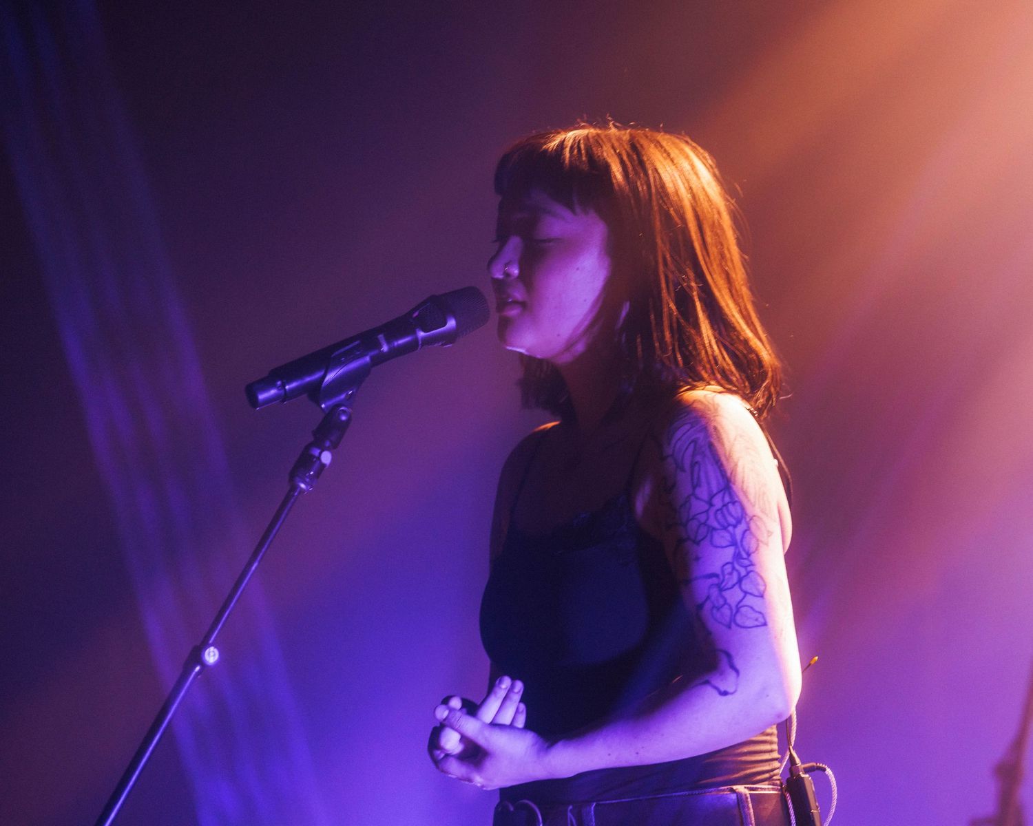 Close up of mxmtoon, with dramatic lighting, performing on her Liminal Space Tour at Gothic Theater in Denver, Colorado