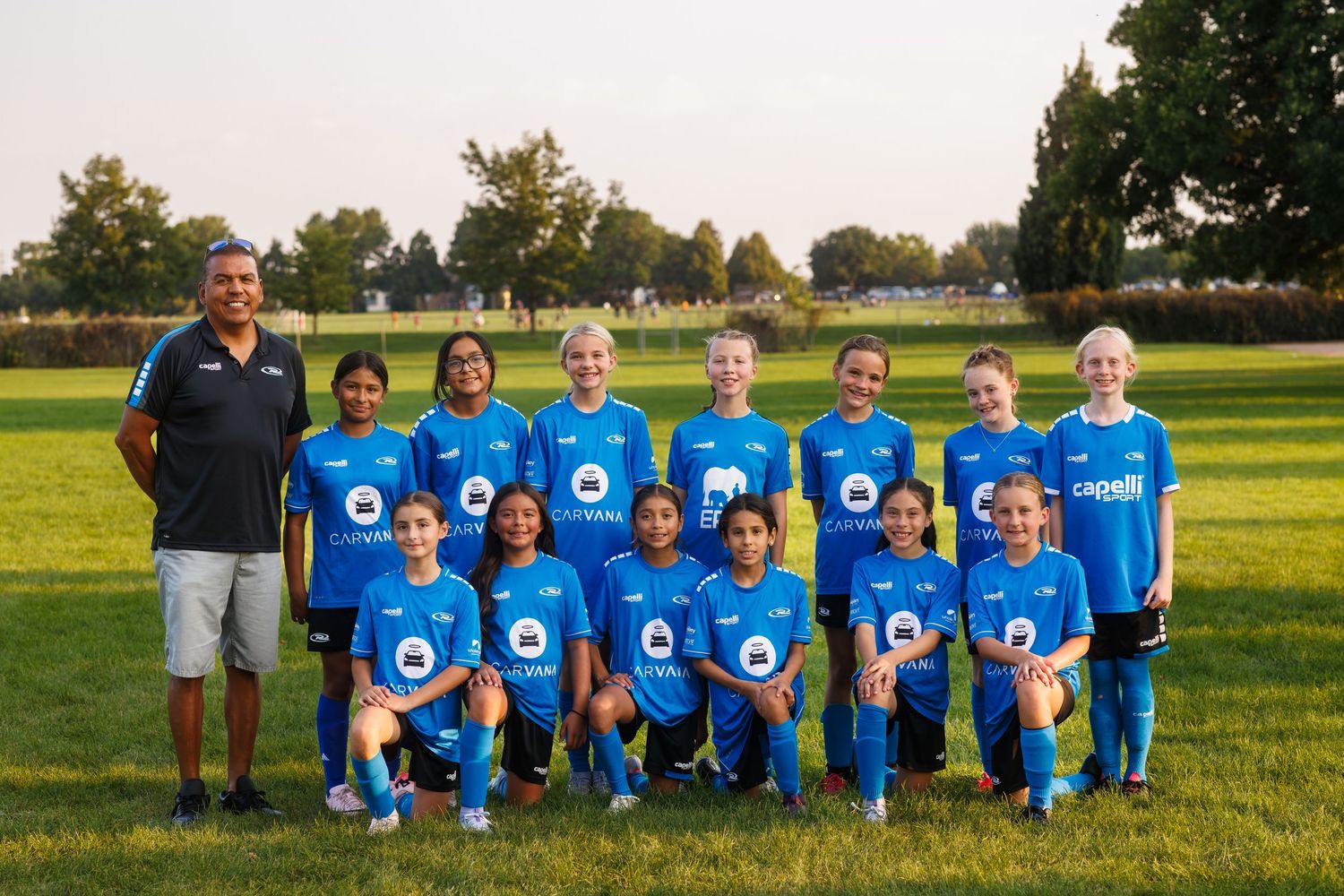 NORCO Rush girls youth team, posing together on a field with their coach