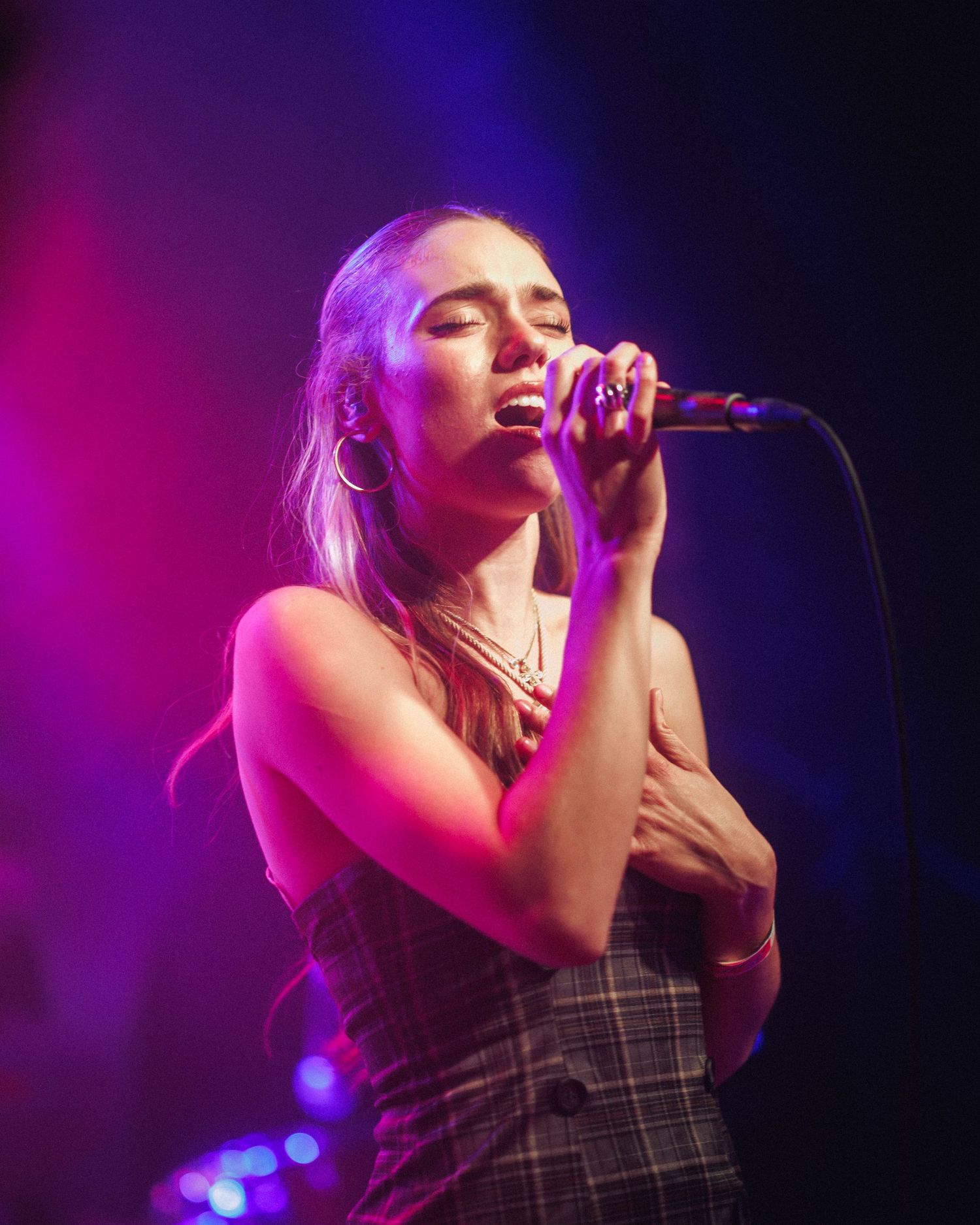 Close up photo, dramatic stage lighting of Kenzie Cait, singing passionately, at Lost Lake Denver while on The Over Nostalgic Tour