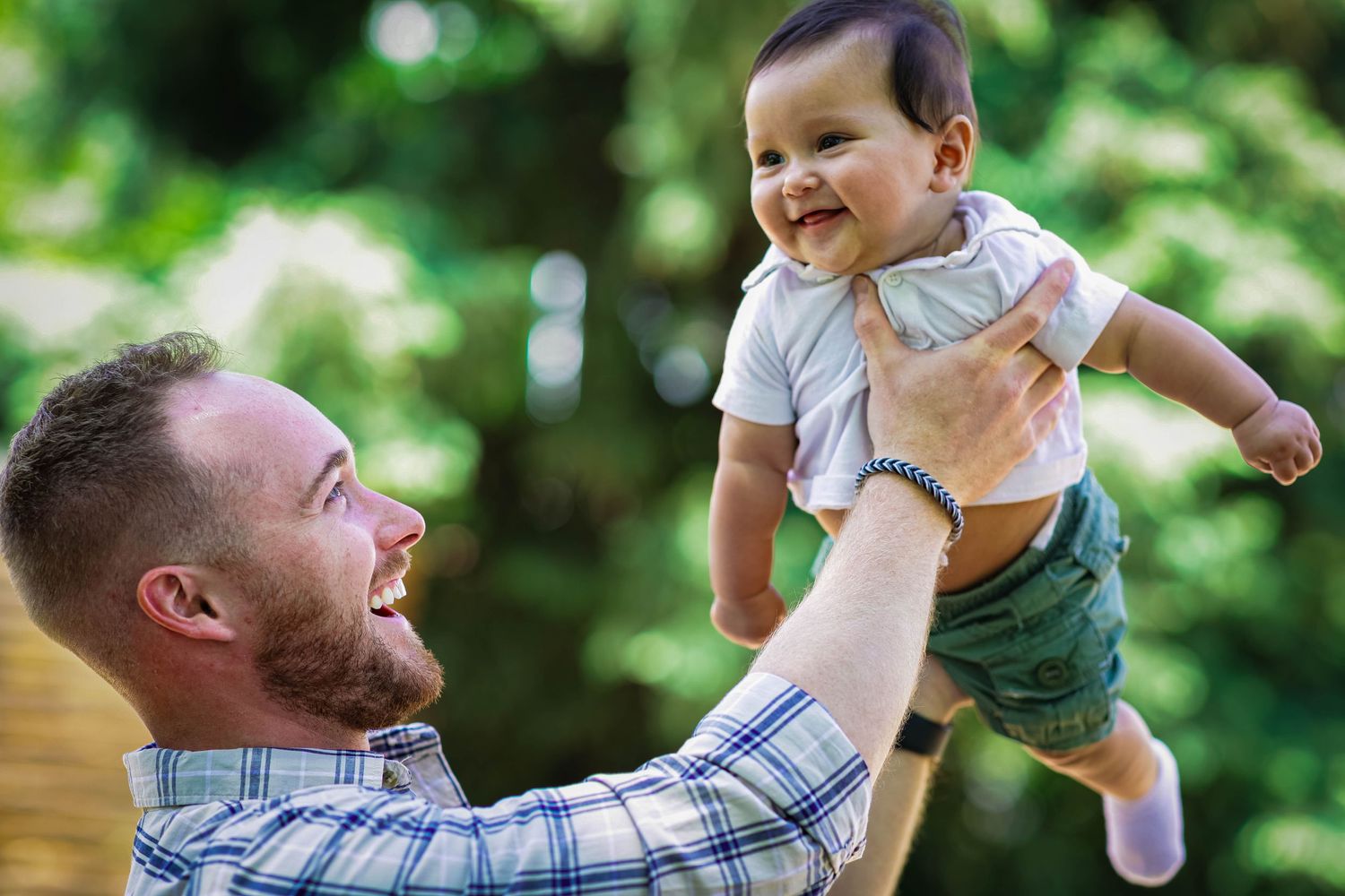 Father lifting his child, laughing together, at the Denver Botanic Gardens