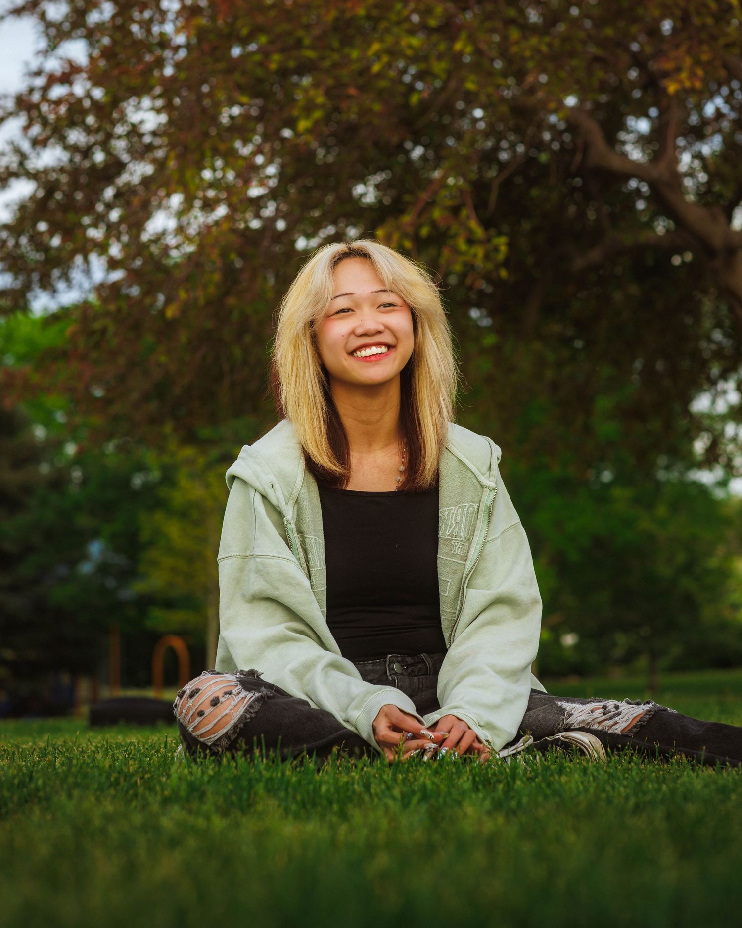 Senior portrait sitting and smiling with sunset landscape at Arapahoe Park