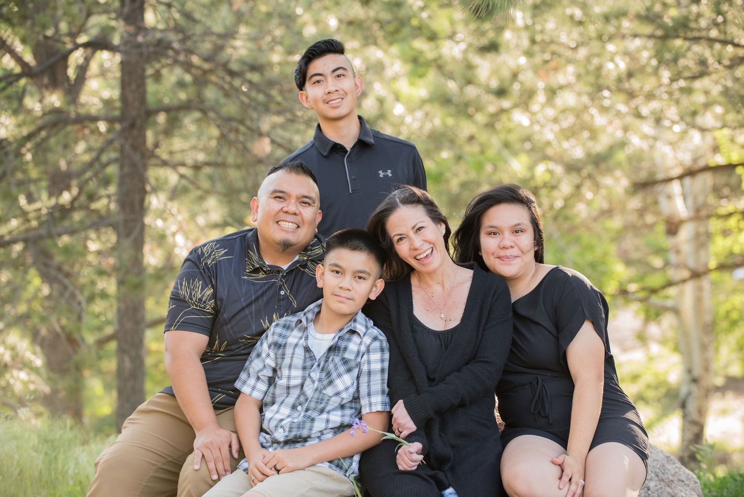 Colorado Springs family portrait of five family members smiling together among pine trees.