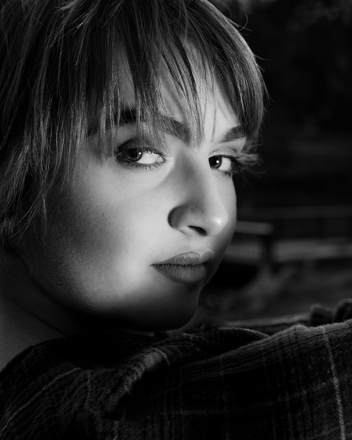 High school senior portrait in black and white with dramatic side lighting and a confident expression.