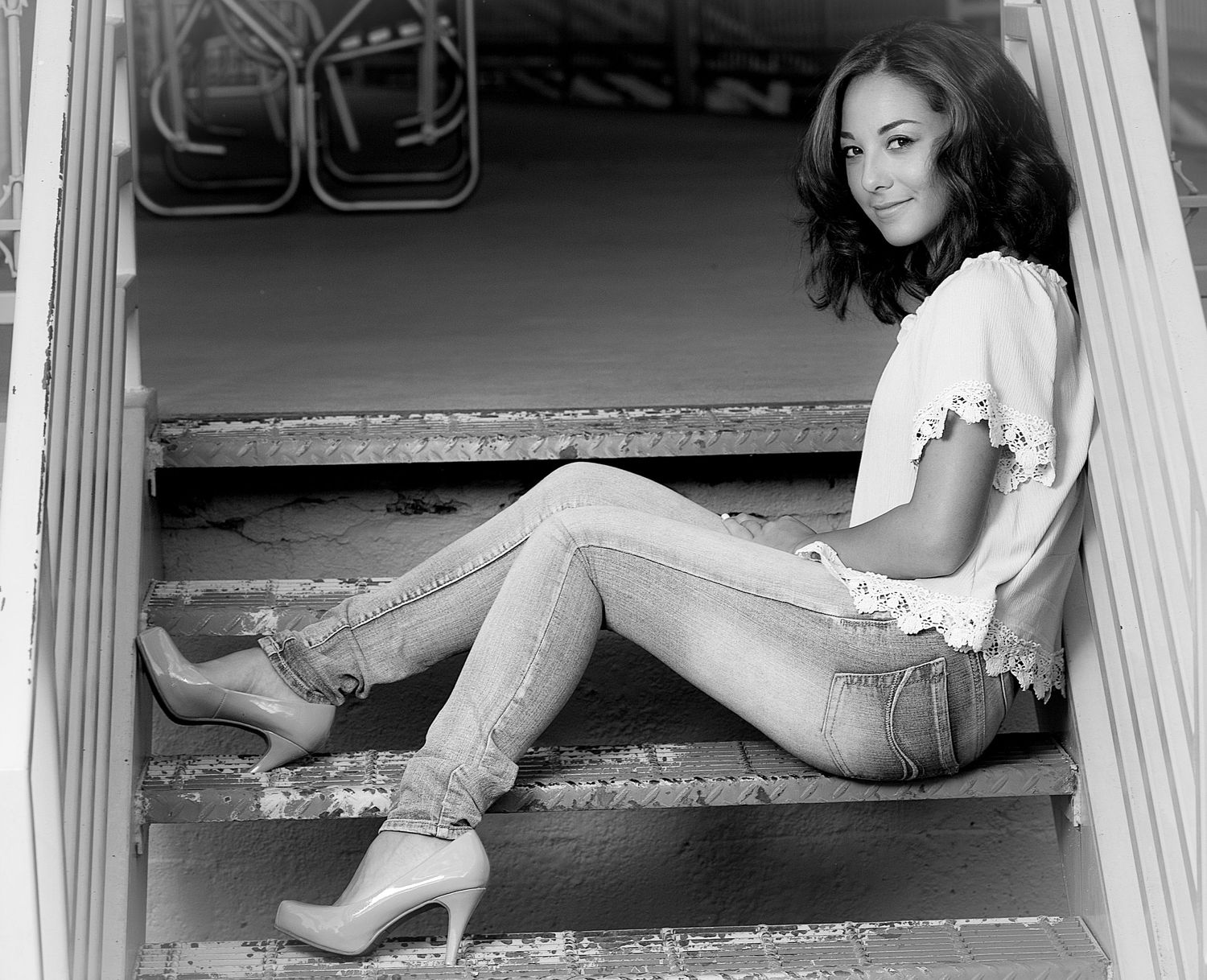 High school senior sitting on metal stairs during an outdoor portrait session.