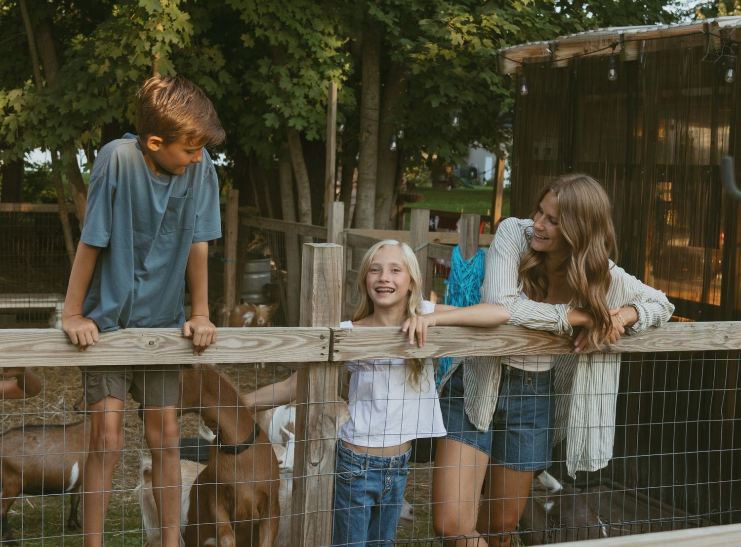 Candid moment of family laughing while leaning against their backyard fence in Hudson Valley, New York