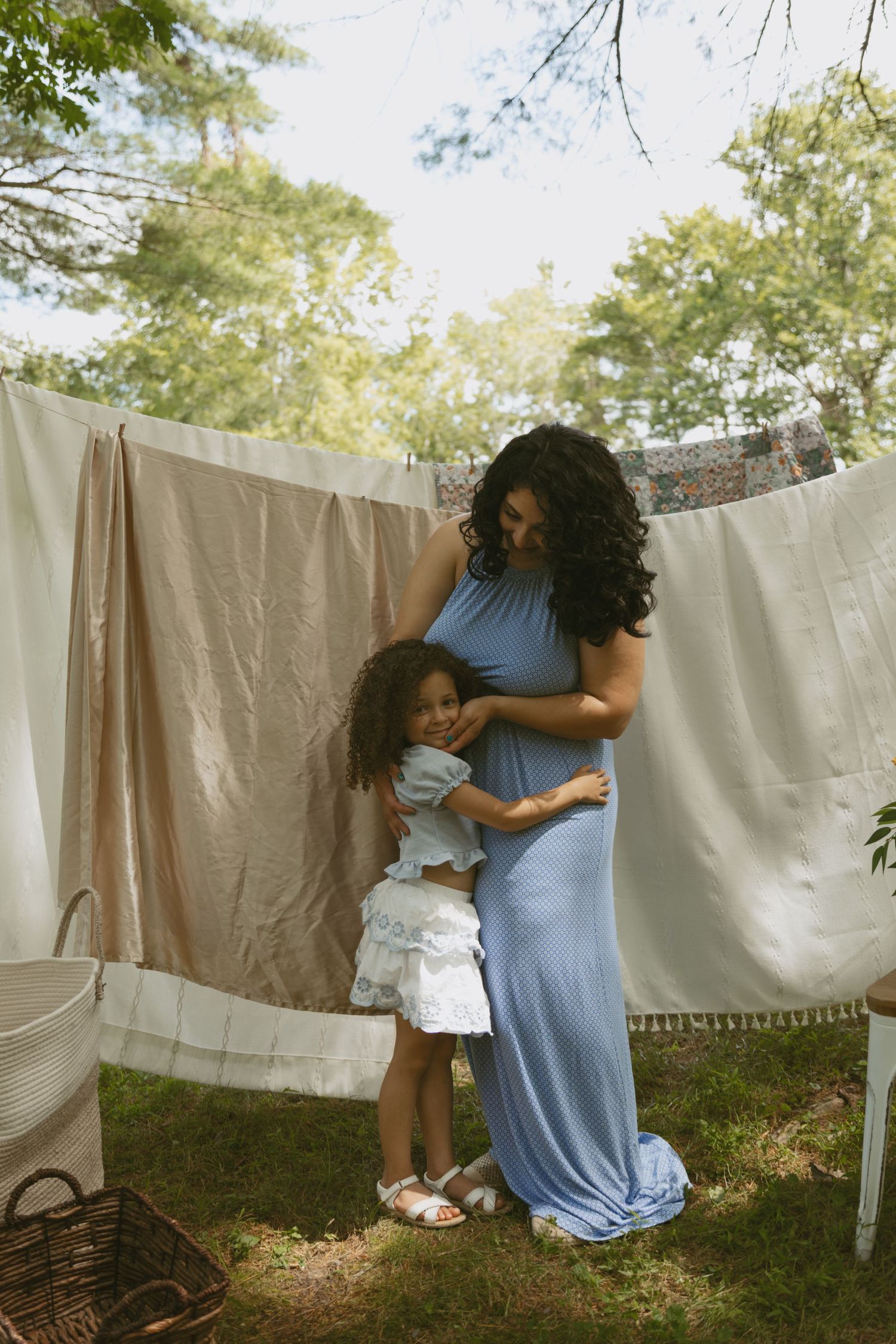 Motherhood photo of a mom hugging her daughter with a clothesline laundry line in the background in Port Jervis, New York.