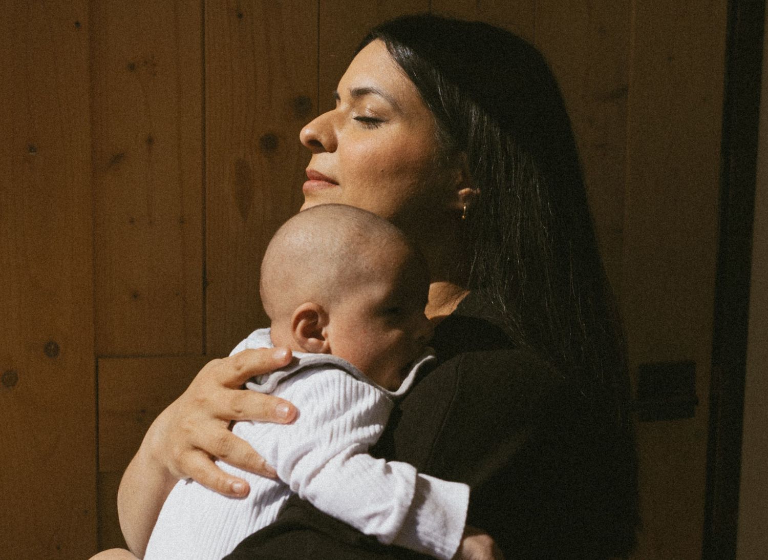 Indoor NJ documentary lifestyle motherhood photoshoot. Mom holding her baby on her chest, taking in the moment.