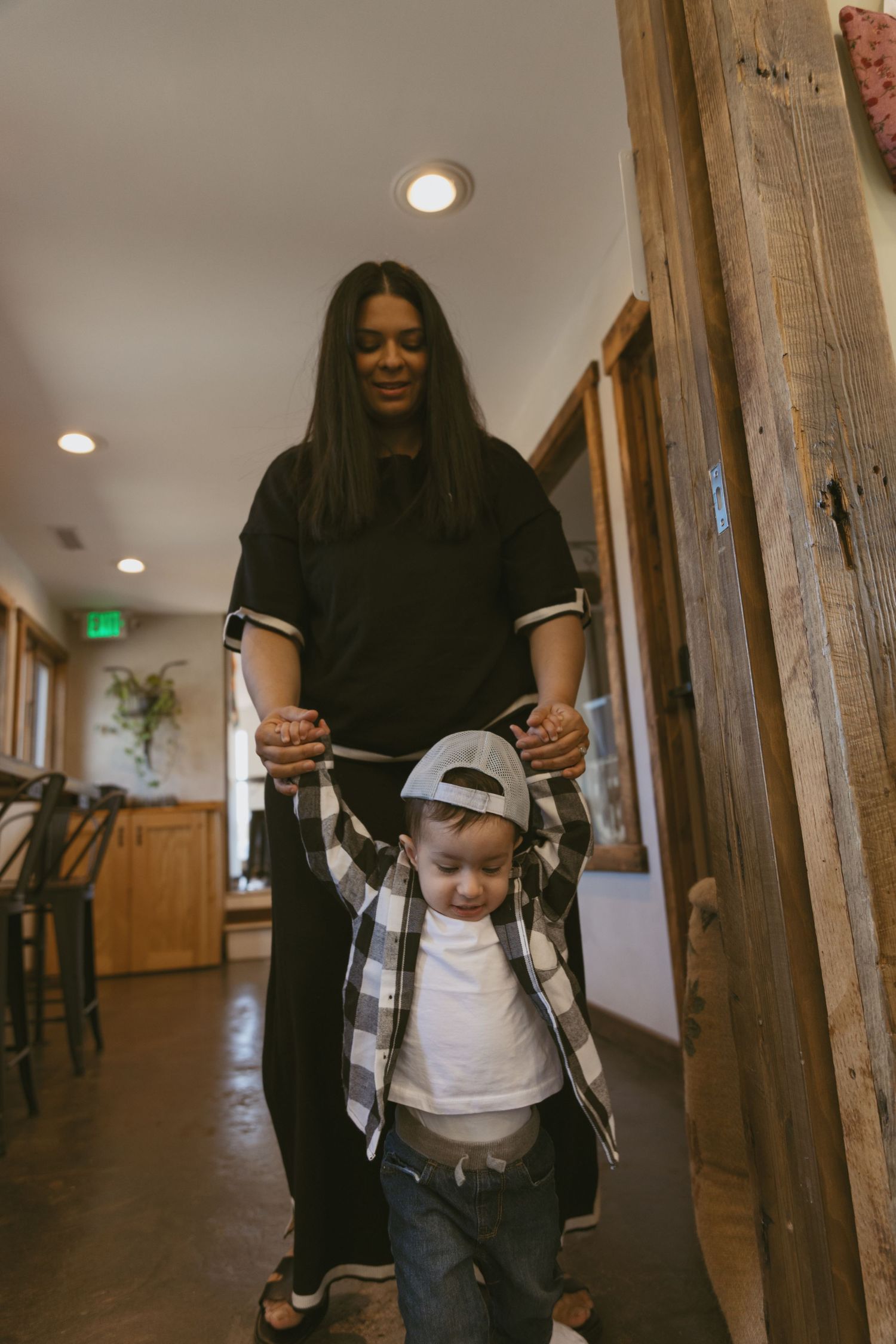 Documentary family lifestyle photoshoot. A mom helping her toddler walk.