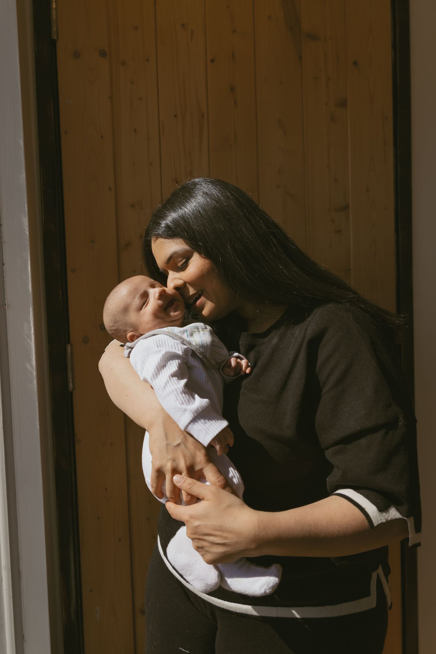 A motherhood photo session of a mom embracing her child, putting her nose to his cheek. Emotive photo that expresses motherly love.
