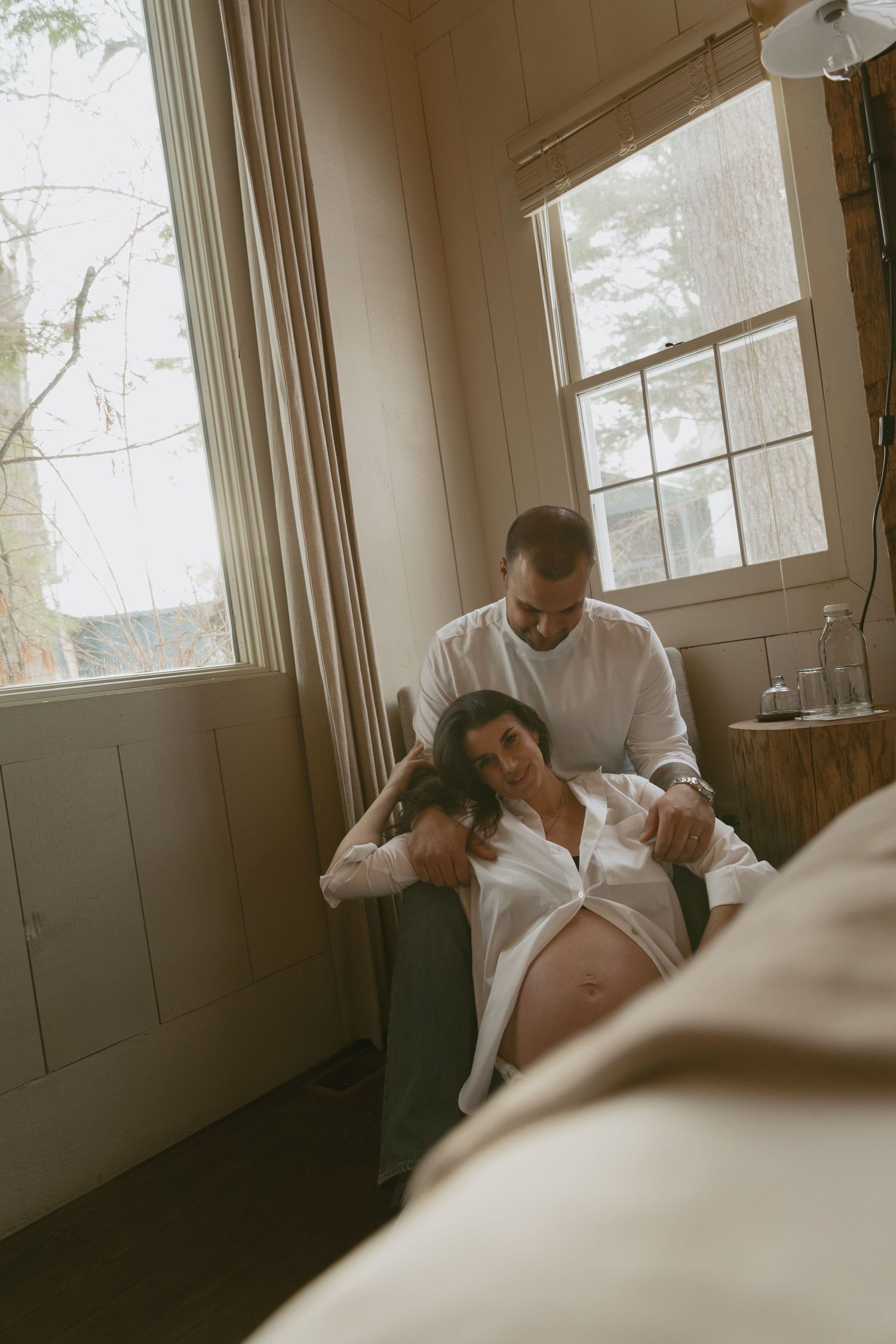 Cozy Editorial indoor maternity photos in the sleepy pine cottage at Cedar Lake Estates in Port Jervis, New York. next to cabin window