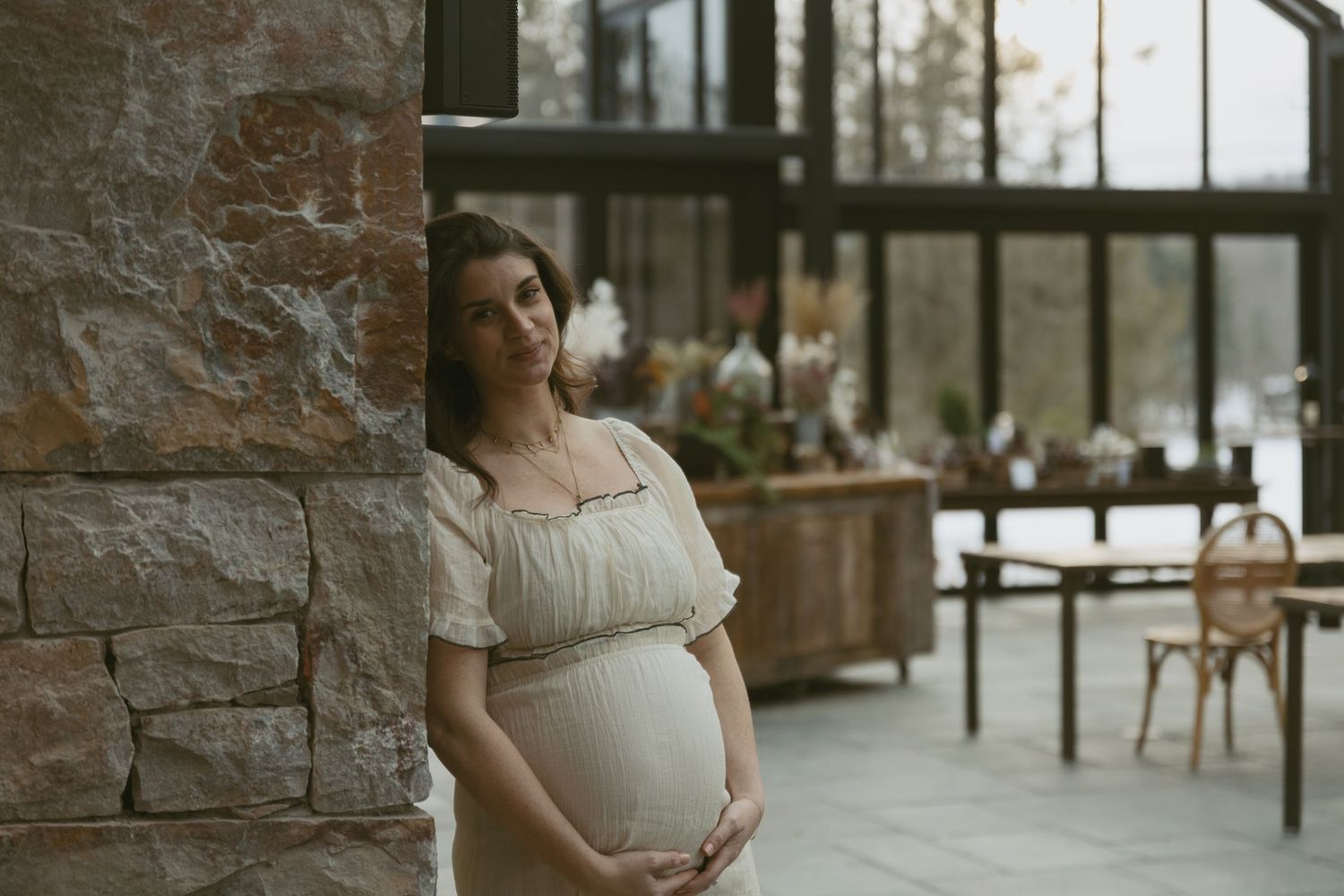 Cozy Editorial indoor maternity photos in the Glasshouse at Cedar Lake Estates in Port Jervis, New York. Mom holding baby bump, fireplace