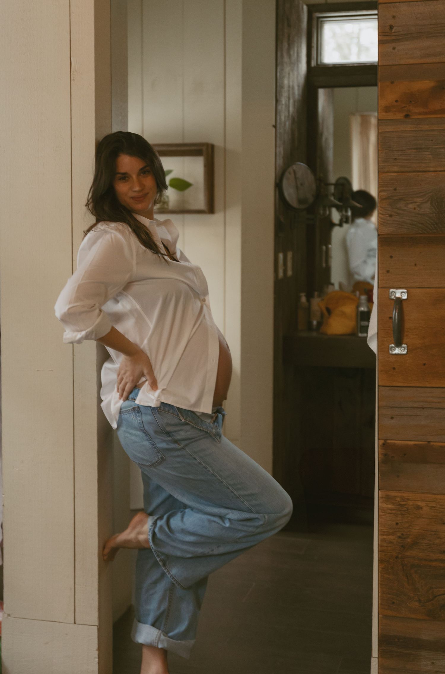 Cozy Editorial indoor maternity photos in the sleepy pine cottage at Cedar Lake Estates in Port Jervis, New York. Leaning against door frame