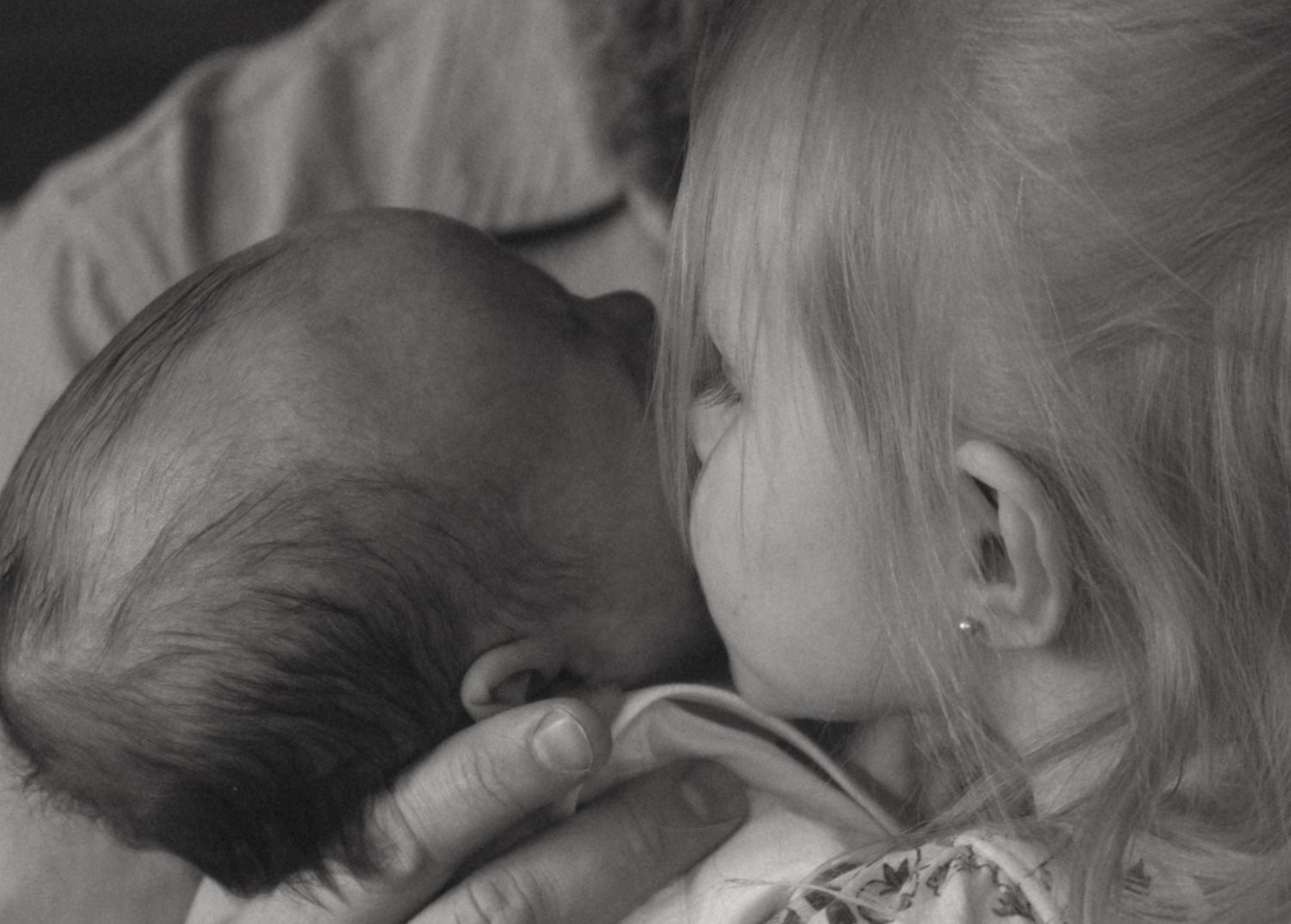 Newborn photos in family cabin in Sullivan County New York, toddler kissing newborns cheek, emotional image